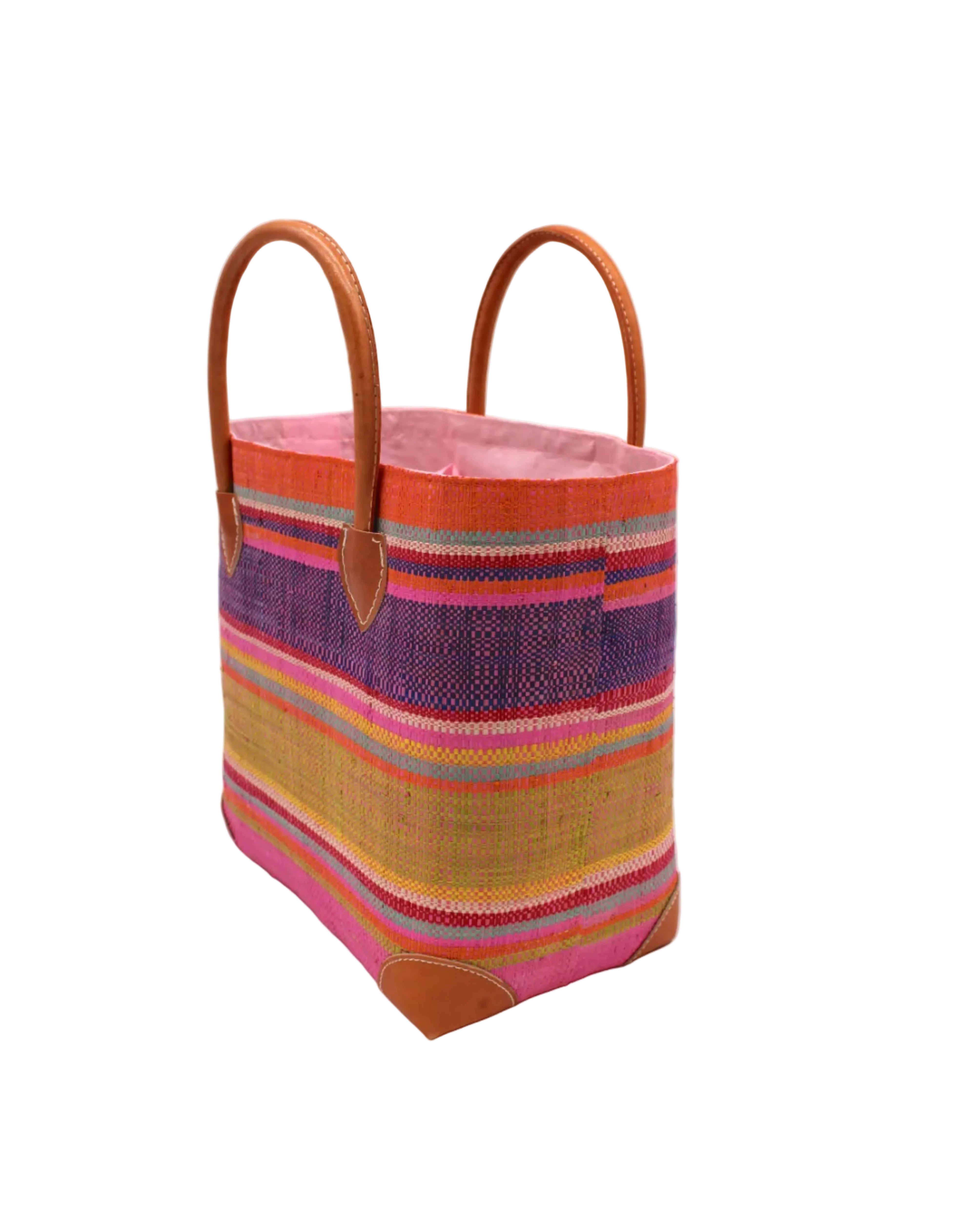 Side view Rayo Stripes Straw Basket Bag Raspberry Swirl handmade loomed natural raffia palm fiber in a multicolor multi width horizontal stripe pattern of coral orange, red, purple, midori lime/green, light pink, yellow, blue, and natural straw color, etc. with leather handles and accents tote beach bag - Shebobo