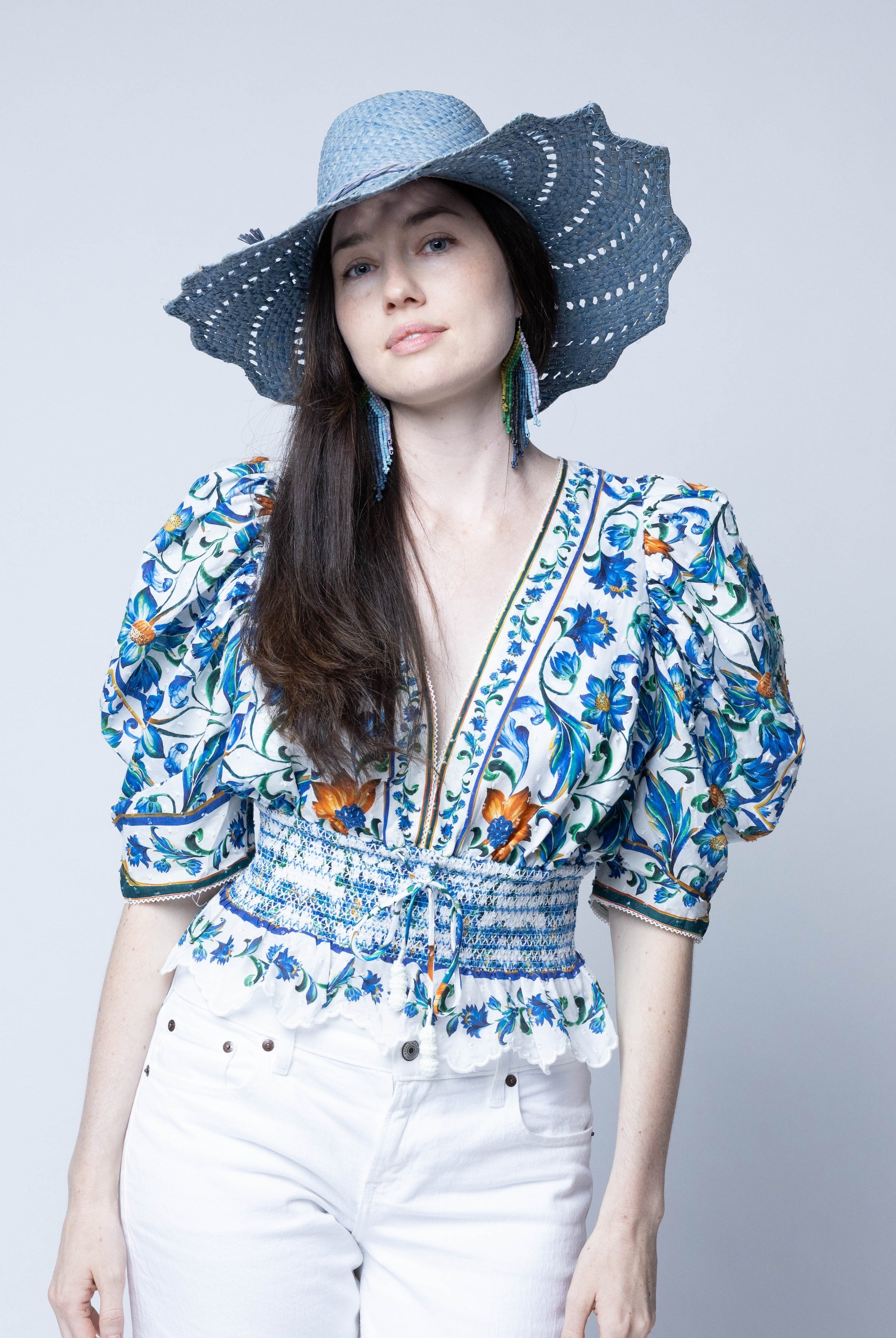 Model wearing Sara 4.5" Brim Woven Straw Sun Hats with Zigzag Edge handmade natural raffia palm fiber in a solid hue of Denim retro/light/blue woven with a subtle crosshatch texture across the crown and spiraling open weave across the brim with matching hat band and zigzag edge - Shebobo