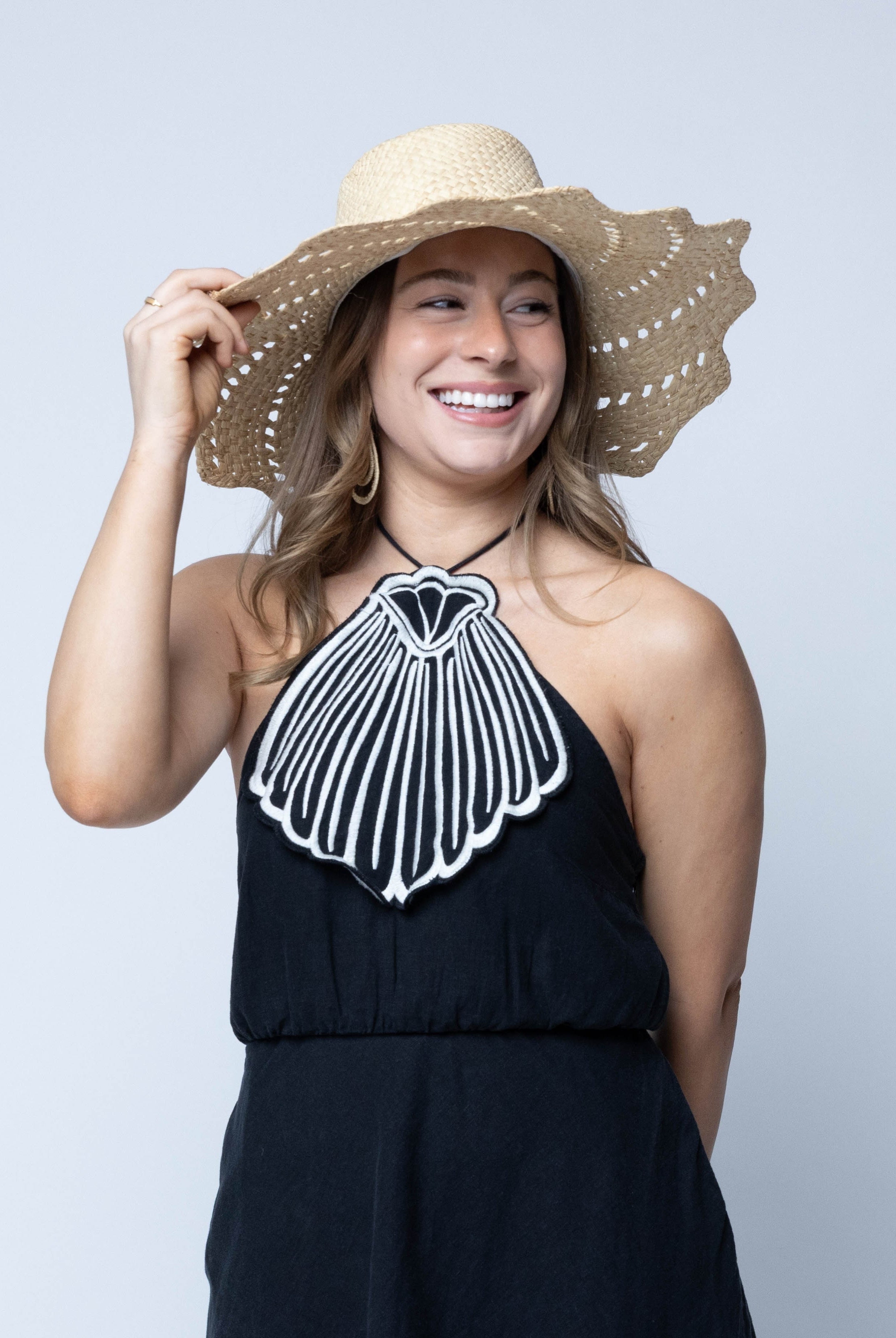 Model wearing Sara 4.5" Brim Woven Straw Sun Hats with Zigzag Edge handmade natural raffia palm fiber in a solid hue of Natural straw color woven with a subtle crosshatch texture across the crown and spiraling open weave across the brim with matching hat band and zigzag edge - Shebobo