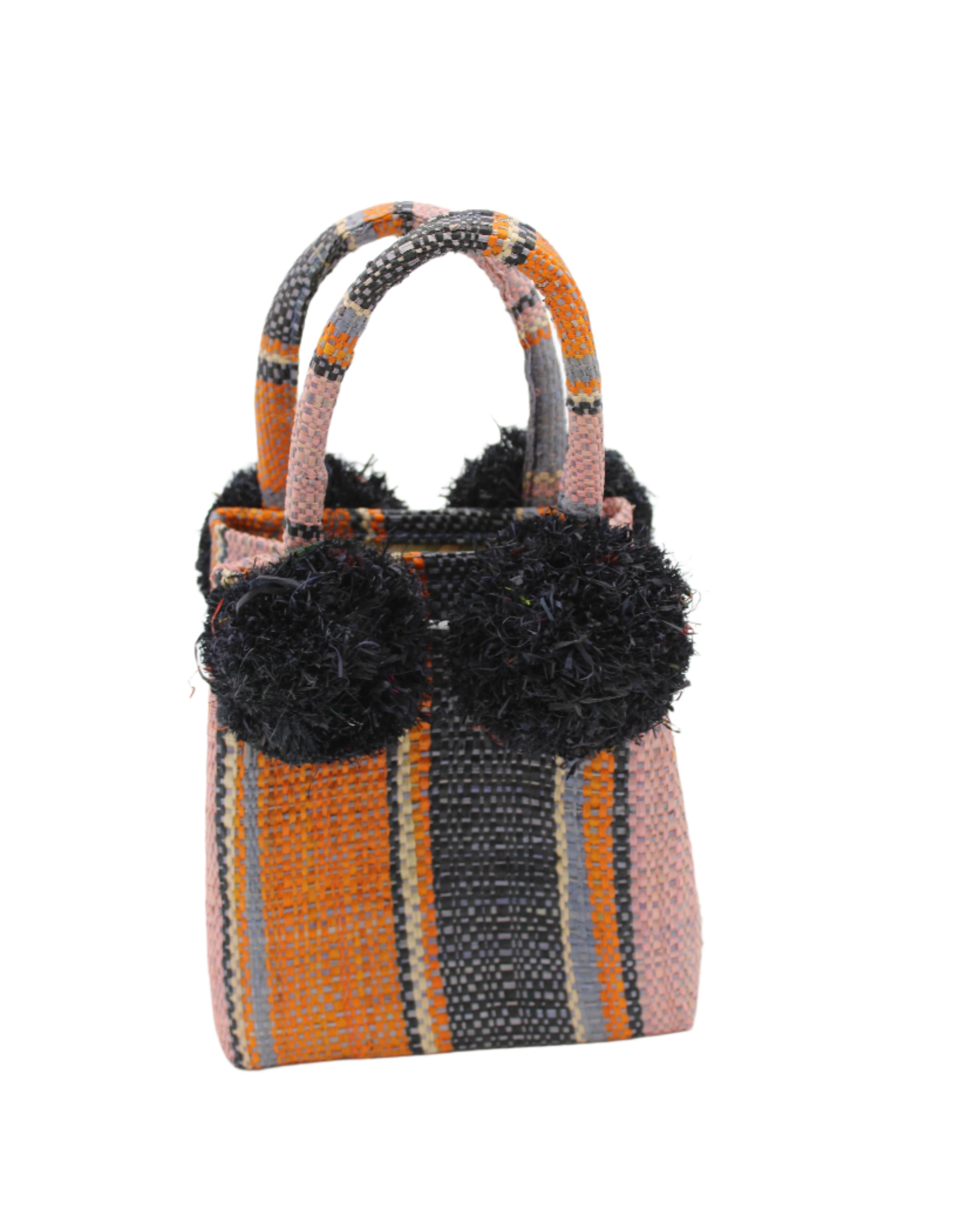 Schooner Retro Swirl Straw Mini Bag with Pompom Accent handmade loomed natural raffia palm fiber in multi width vertical multicolor stripe pattern of denim retro/light/blue, dusk navy/dark/blue, coral orange/red, light pink, black, and natural straw color with four matching raffia pompom embellishments at the base of each handle attachment tiny purse extra small handbag - Shebobo