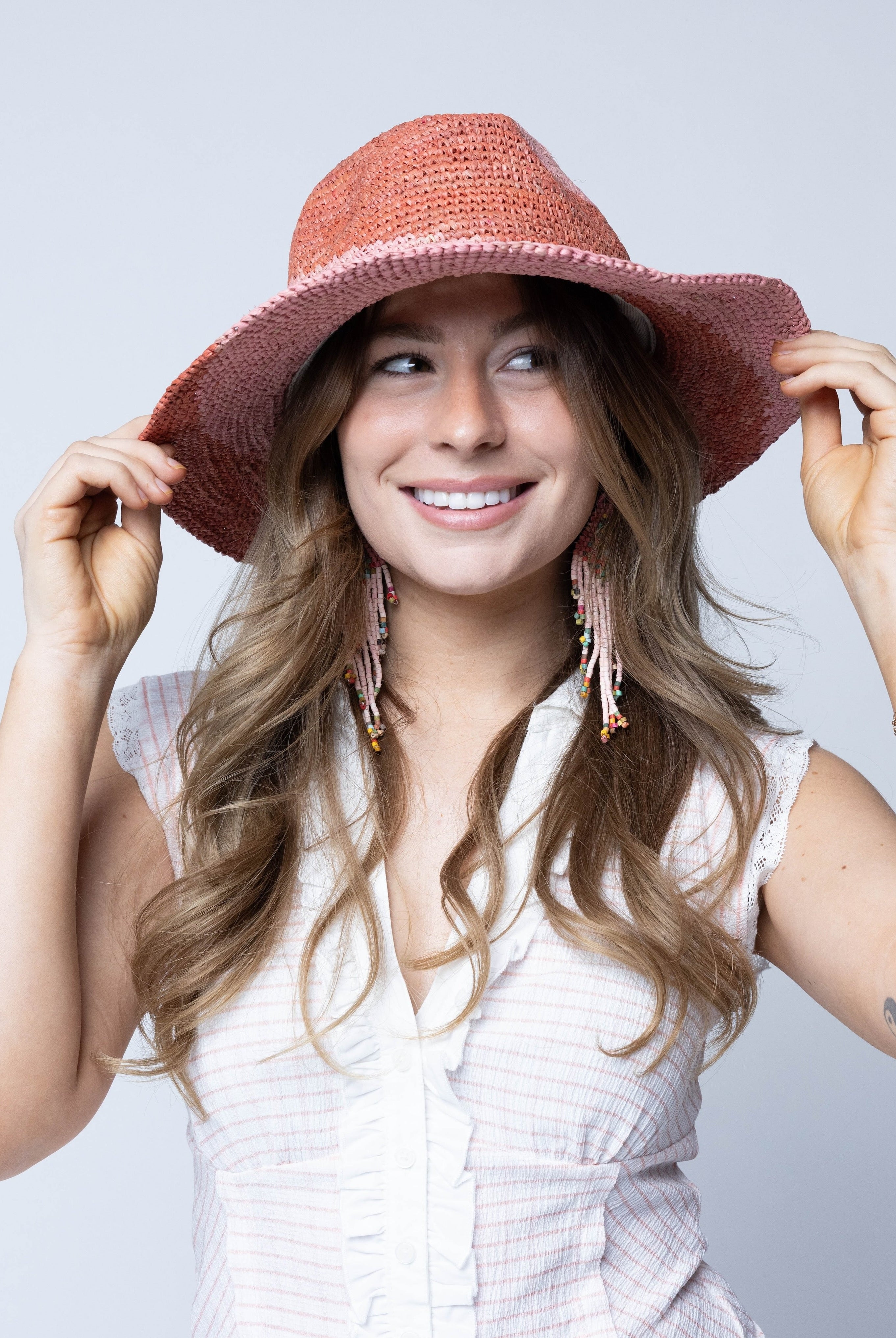 Model wearing Sequoia Blush & Pink 3" Brim Swirl Crochet Panama Unisex Straw Hats handmade crochet natural raffia palm fiber in a two tone color swirl design of blush orange/pink and pink pale/light/pink spiraling together from wide bands around the brim to a narrow twist at the top of the crown - Shebobo