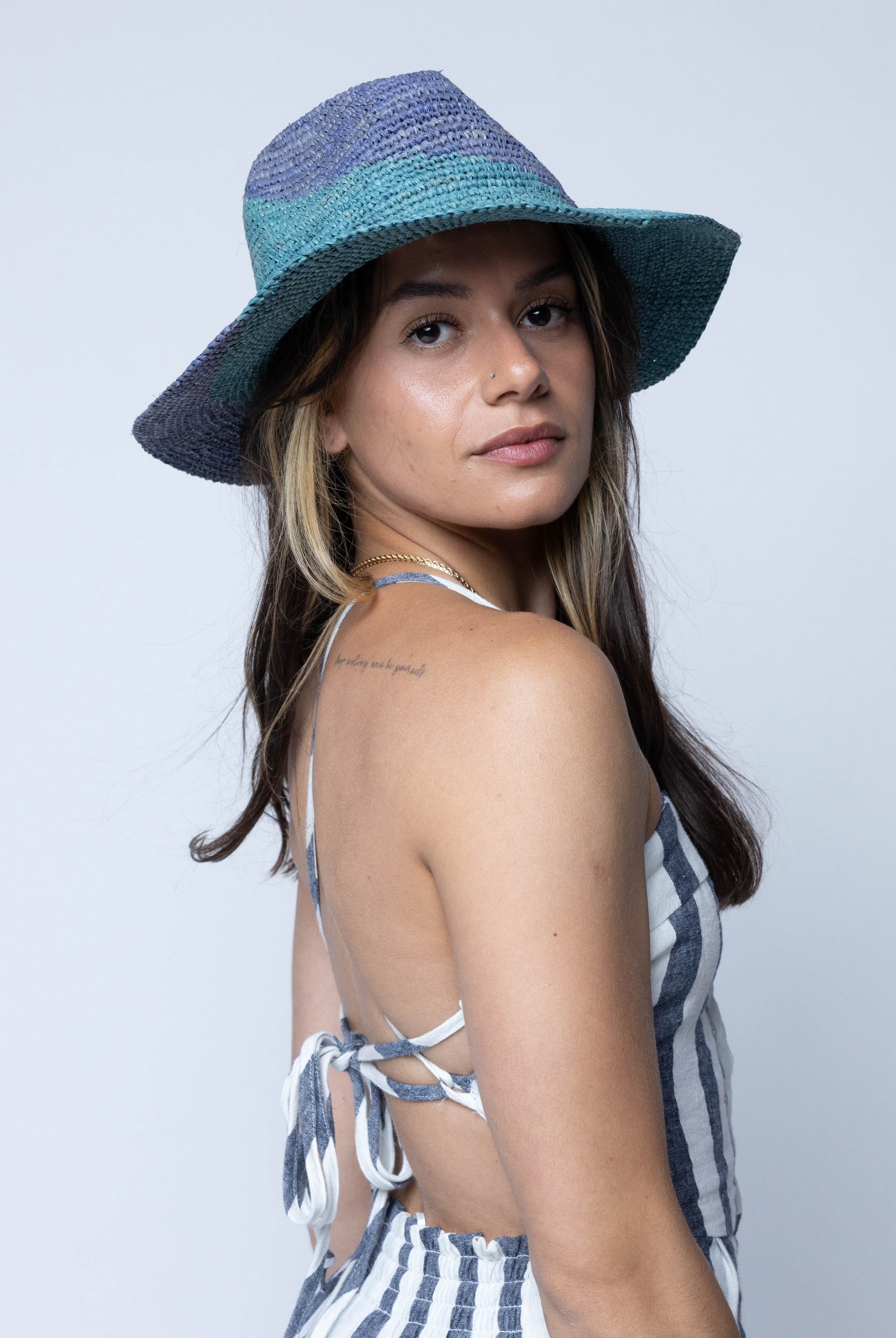 Model wearing Sequoia Denim & Turquoise 3" Brim Swirl Crochet Panama Unisex Straw Hats handmade crochet natural raffia palm fiber in a two tone color swirl design of denim retro/light/blue and turquoise light/blue/green spiraling together from wide bands around the brim to a narrow twist at the top of the crown - Shebobo