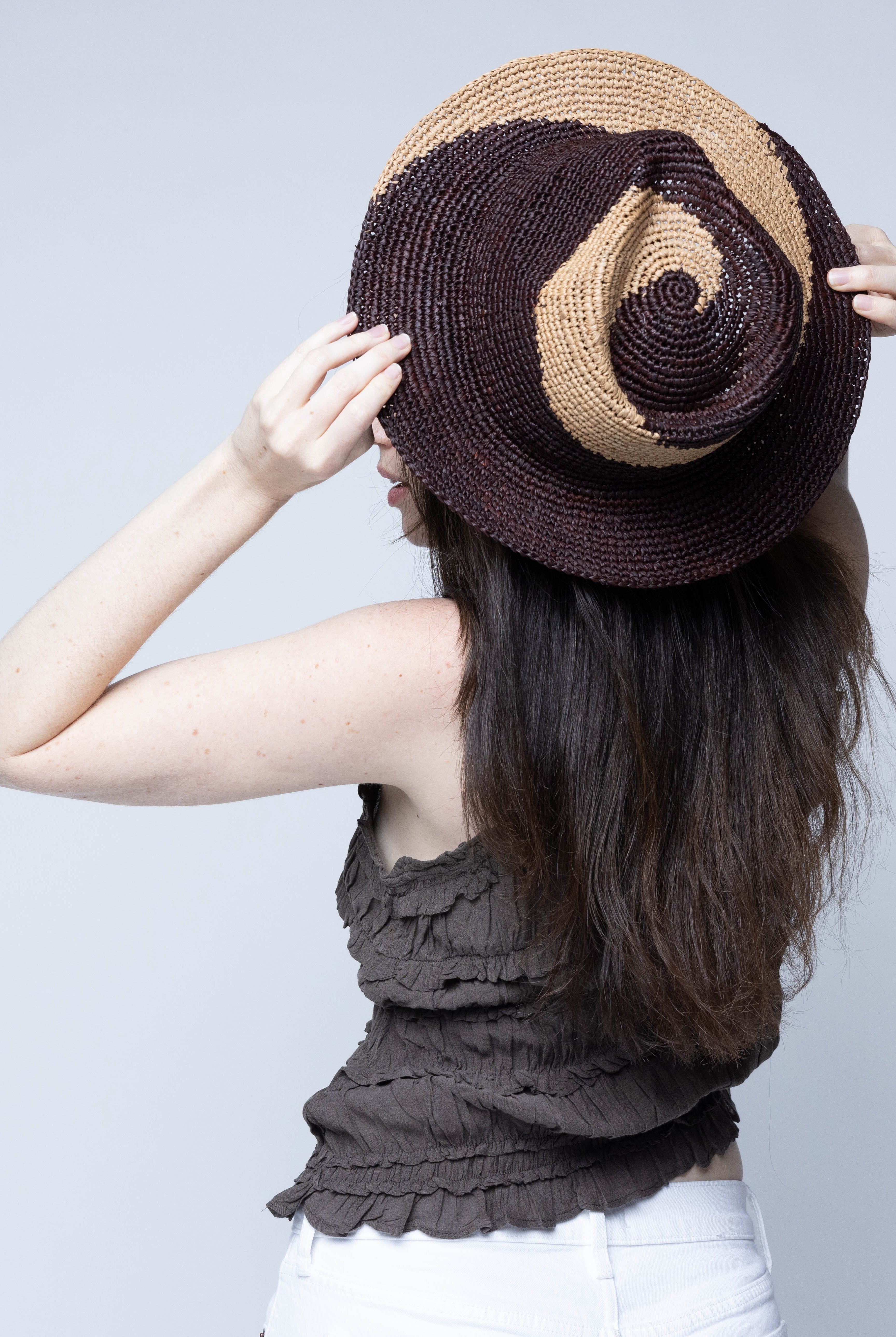 Model wearing Sequoia Cappuccino & Mocha 3" Brim Swirl Crochet Panama Unisex Straw Hats handmade crochet natural raffia palm fiber in a two tone color swirl design of cappuccino tea/light/brown and mocha dark/chocolate/brown spiraling together from wide bands around the brim to a narrow twist at the top of the crown - Shebobo
