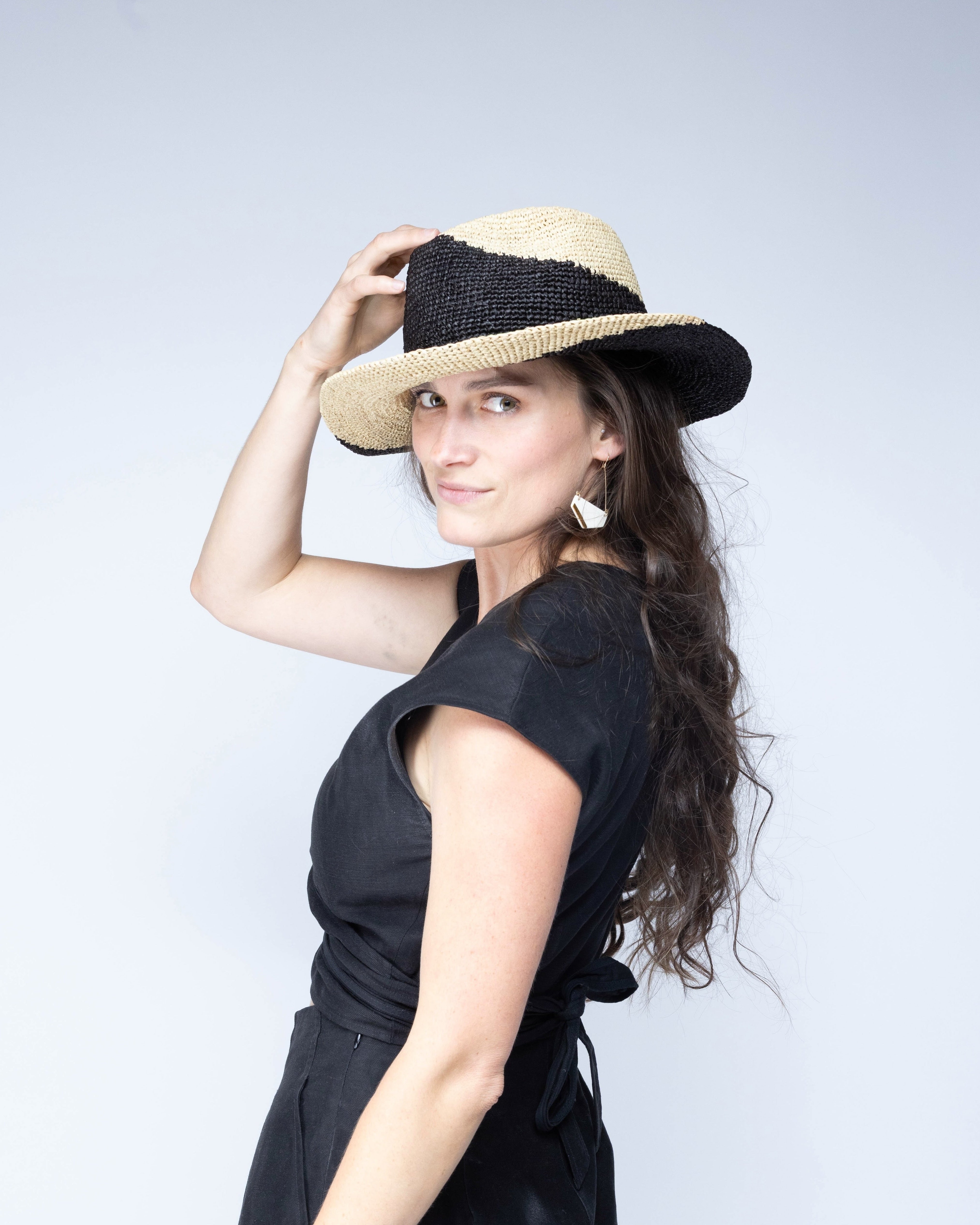 Model wearing Sequoia Black and Natural 3" Brim Swirl Crochet Panama Unisex Straw Hats handmade crochet natural raffia palm fiber in a two tone color swirl design of black and natural straw color spiraling together from wide bands around the brim to a narrow twist at the top of the crown - Shebobo
