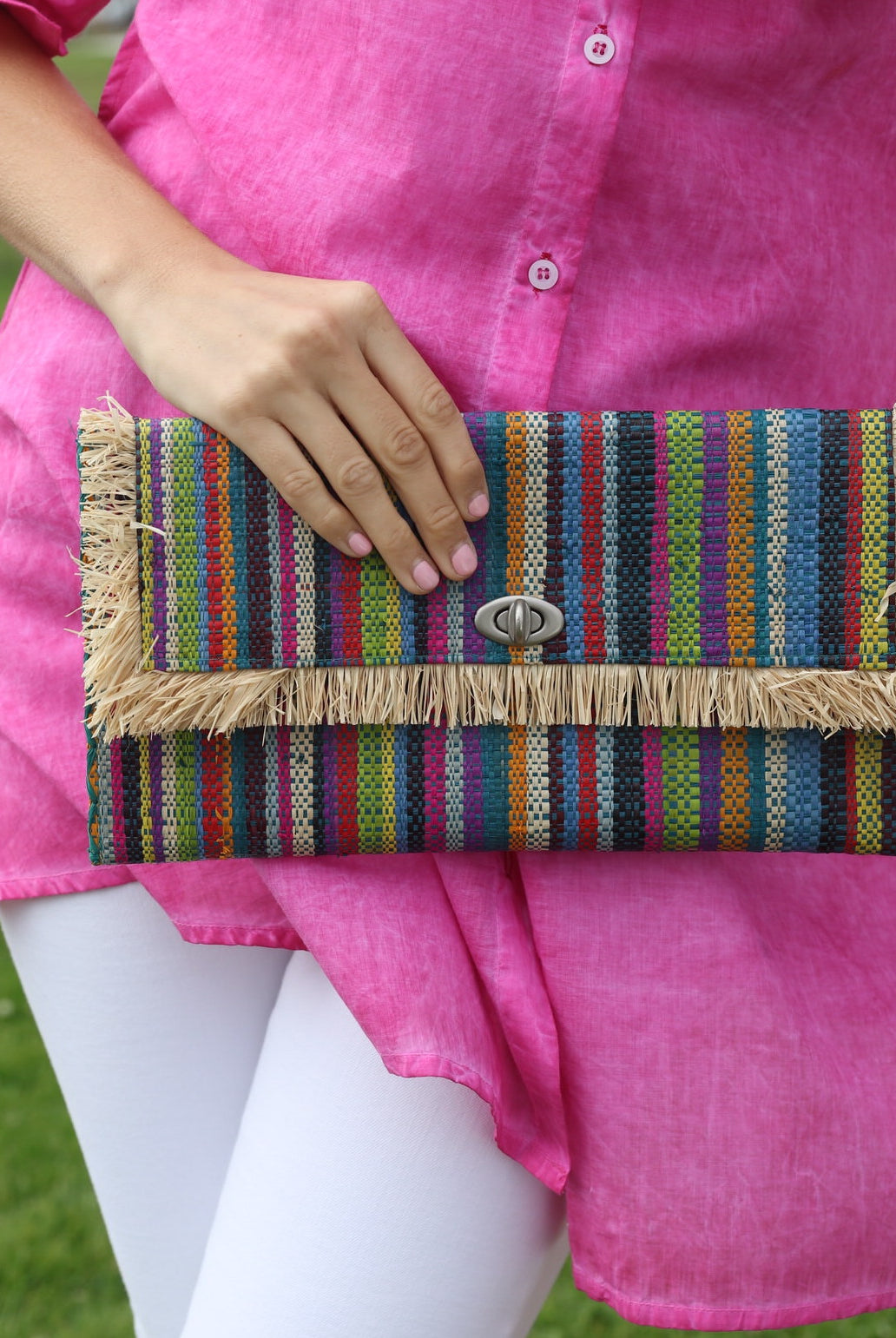 Model wearing Sophie Turquoise Stripes Multicolor Straw Clutch handmade loomed raffia purse handbag with raw fringe edge detailing turquoise, blue, natural, black, red, yellow, purple, orange, green, fuchsia, etc. multi width multicolor vertical stripe pattern envelope shaped bag - Shebobo