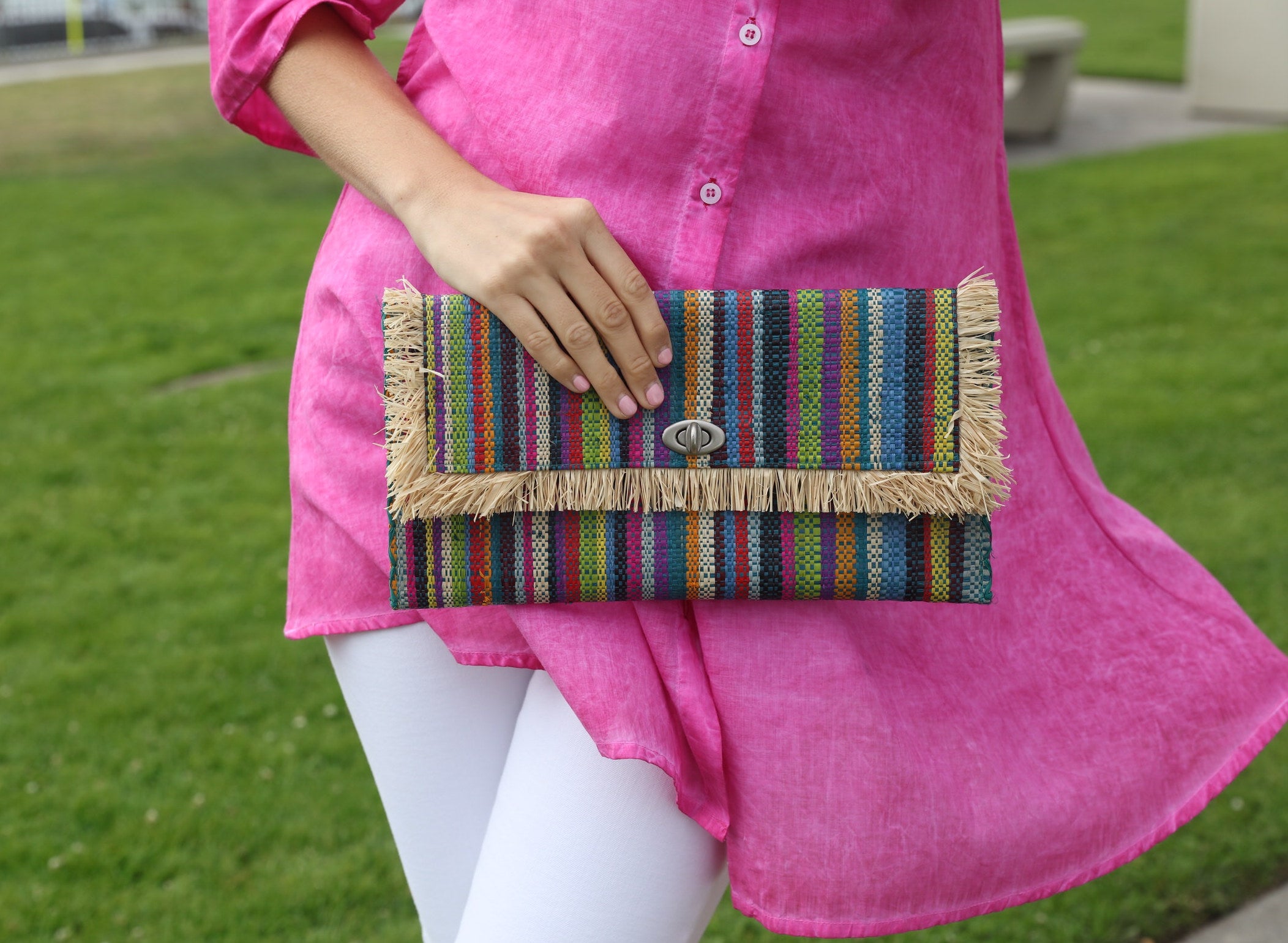 Model wearing Sophie Turquoise Stripes Multicolor Straw Clutch handmade loomed raffia purse handbag with raw fringe edge detailing turquoise, blue, natural, black, red, yellow, purple, orange, green, fuchsia, etc. multi width multicolor vertical stripe pattern envelope shaped bag - Shebobo