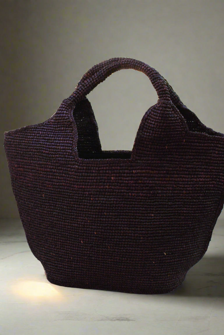 Lifestyle view St. Tropez Heart Shaped Crochet Straw Basket Handbag handmade crochet natural raffia palm fiber in a solid hue of Mocha chocolate/dark/brown with a subtle link texture beach bag shoulder bag - Shebobo