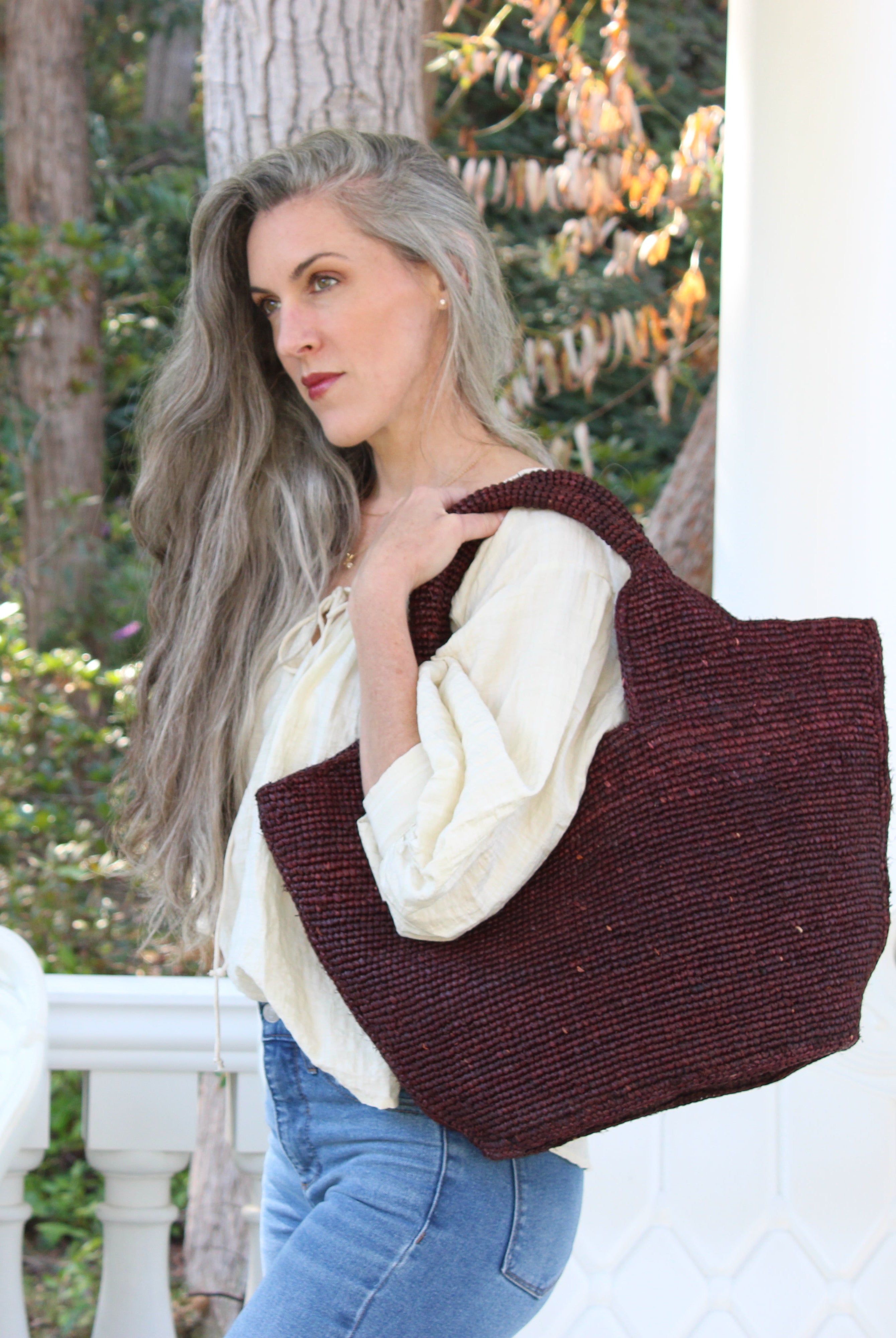 Model wearing St. Tropez Heart Shaped Crochet Straw Basket Handbag handmade crochet natural raffia palm fiber in a solid hue of Mocha chocolate/dark/brown with a subtle link texture beach bag shoulder bag - Shebobo