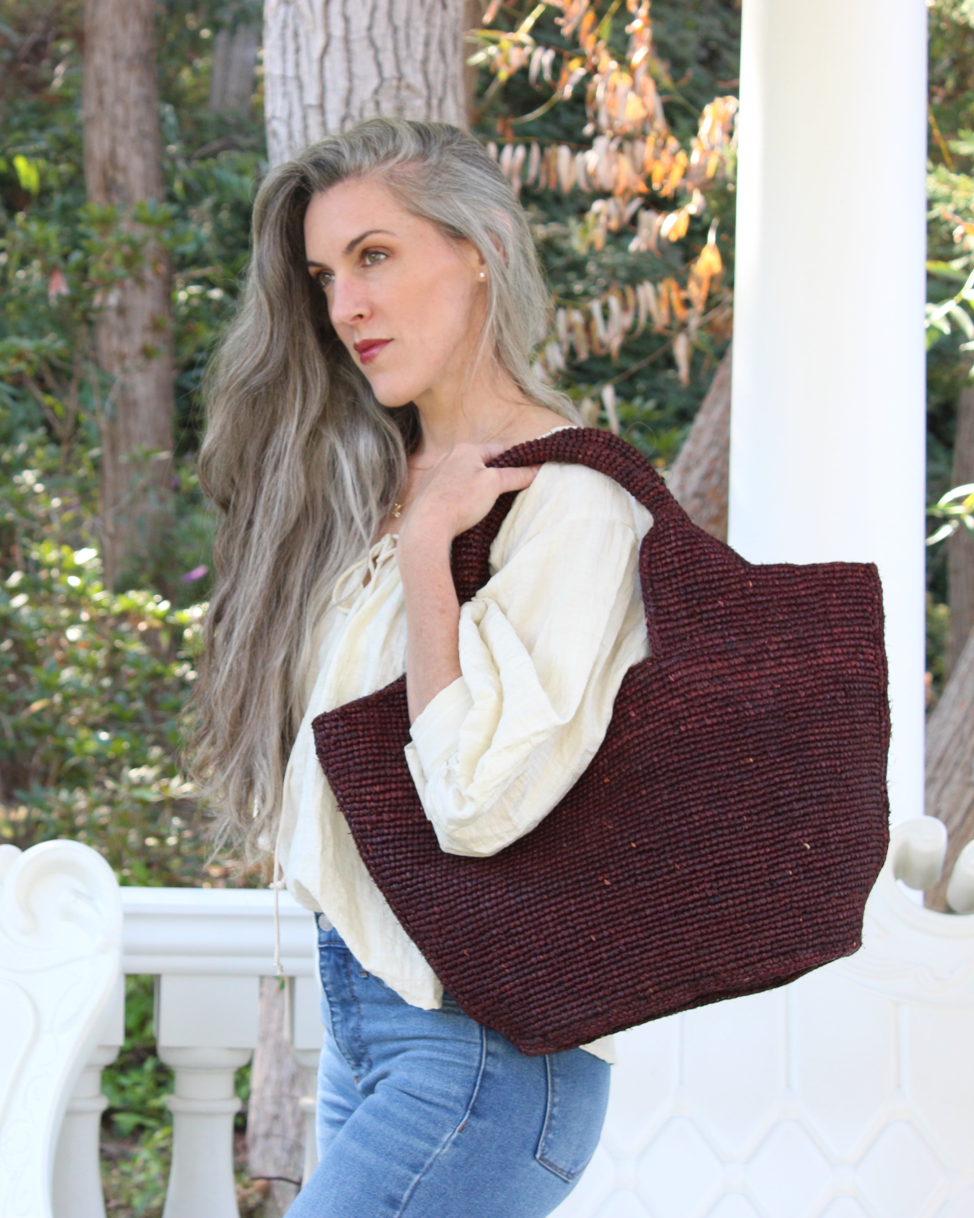 Model wearing St. Tropez Heart Shaped Crochet Straw Basket Handbag handmade crochet natural raffia palm fiber in a solid hue of Mocha chocolate/dark/brown with a subtle link texture beach bag shoulder bag - Shebobo