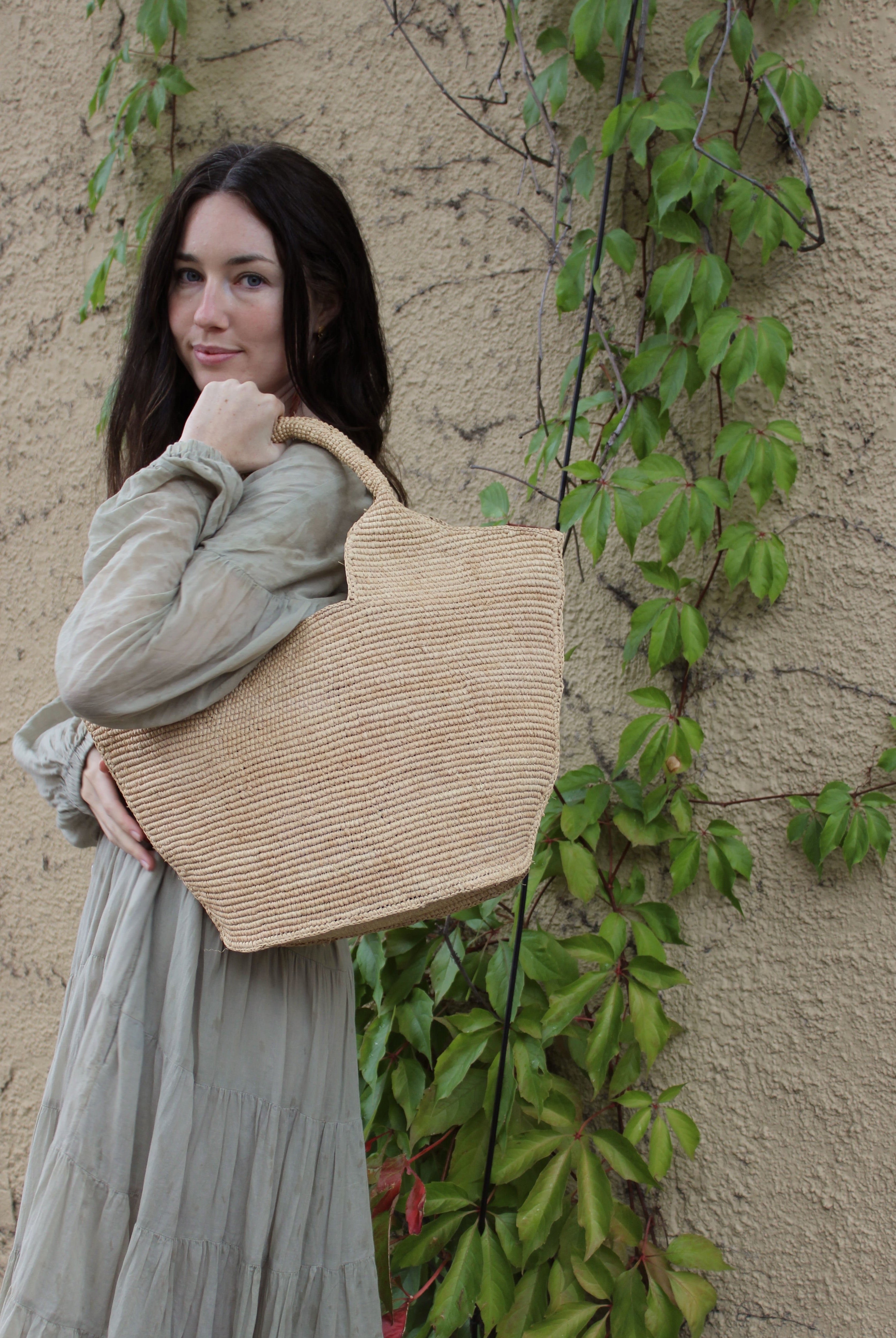 Model wearing St. Tropez Heart Shaped Crochet Straw Basket Handbag handmade crochet natural raffia palm fiber in a solid hue of natural straw color with a subtle link texture beach bag shoulder bag - Shebobo