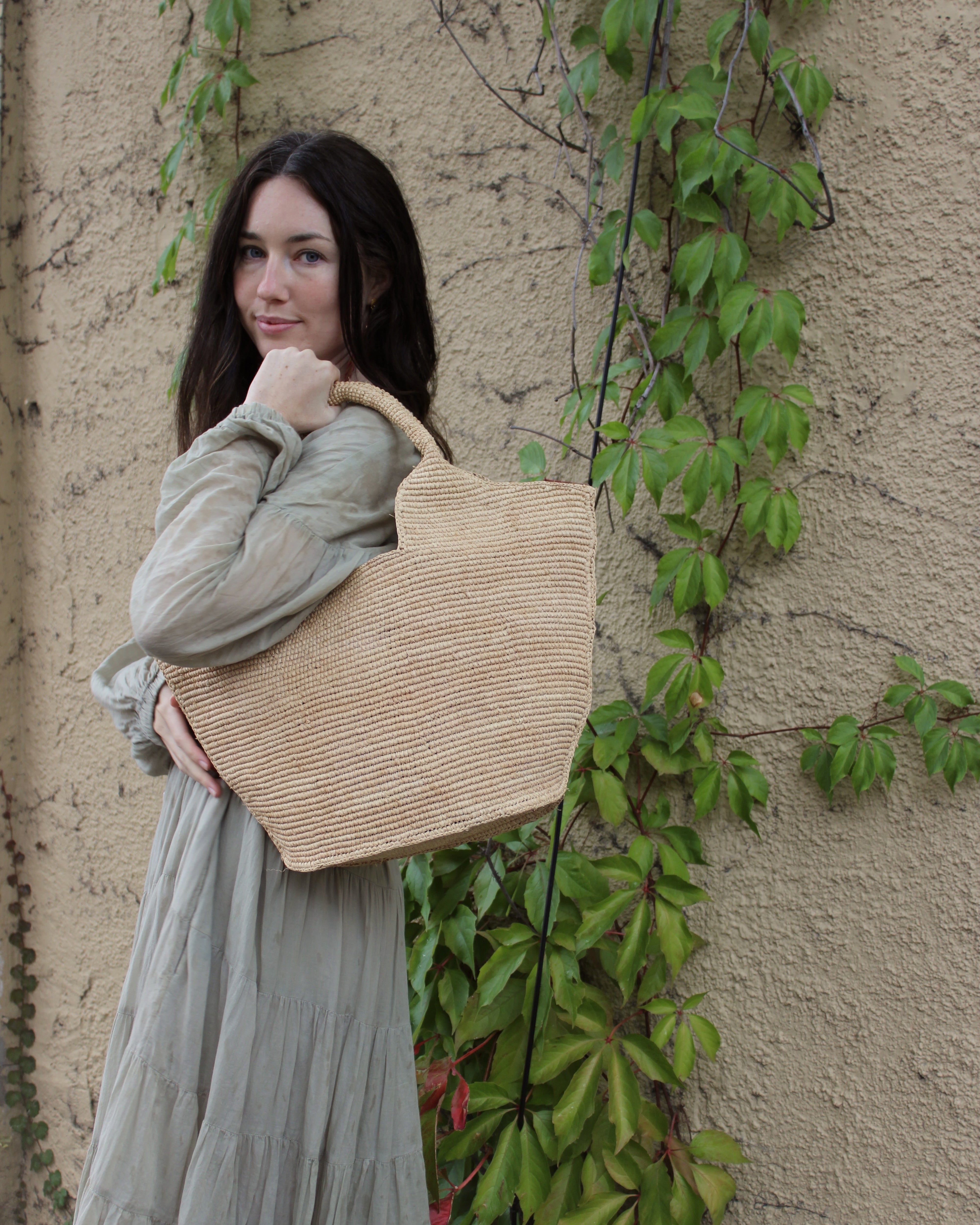 Model wearing St. Tropez Heart Shaped Crochet Straw Basket Handbag handmade crochet natural raffia palm fiber in a solid hue of natural straw color with a subtle link texture beach bag shoulder bag - Shebobo