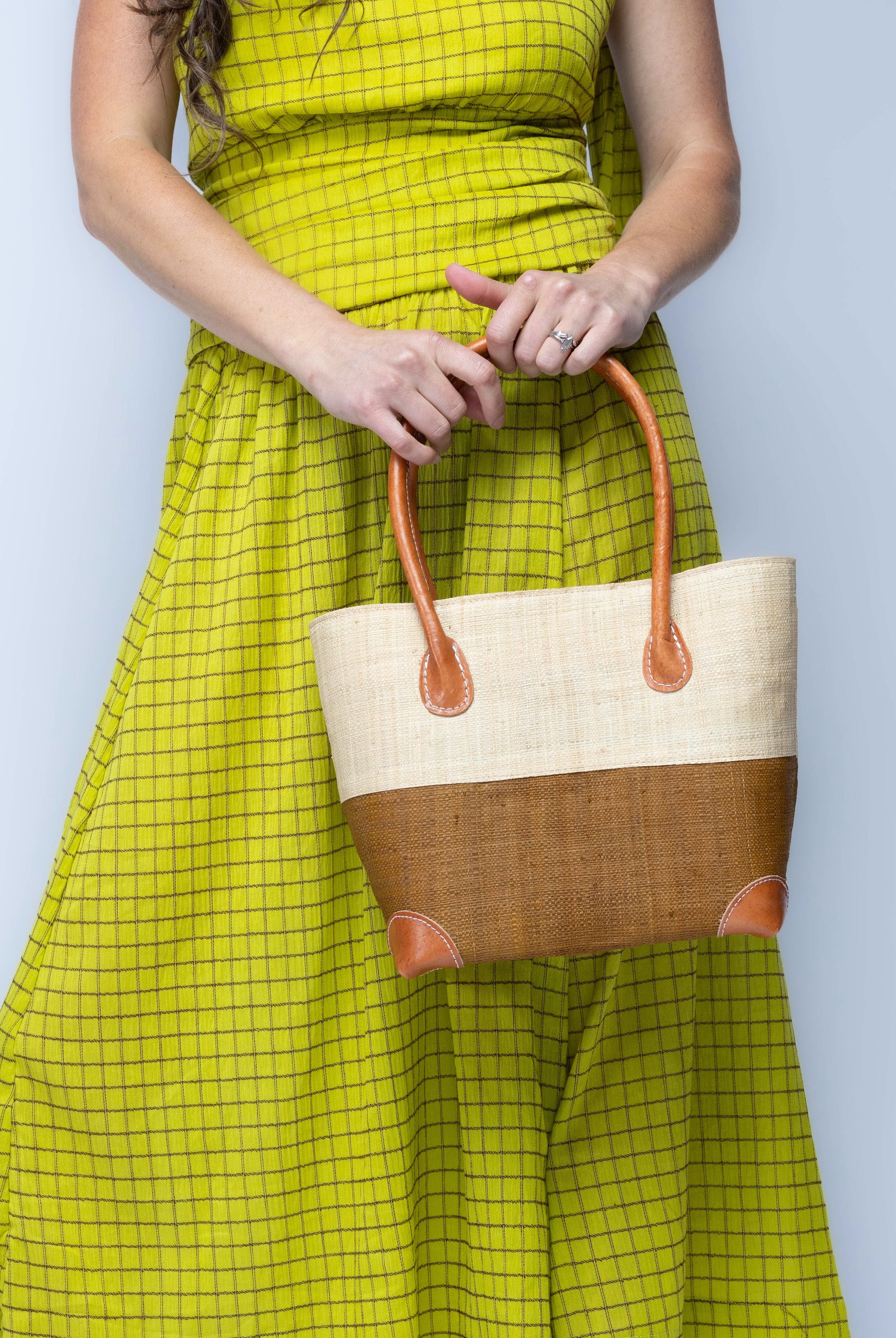 Model wearing Small Trinidad Natural and Tobacco Two Tone Straw Basket Bag handmade loomed raffia palm fiber in a two tone color block pattern with tobacco cinnamon/dark/brown on the bottom half and natural straw color on the top half of the bag with leather handles and accents beach bag tote purse - Shebobo