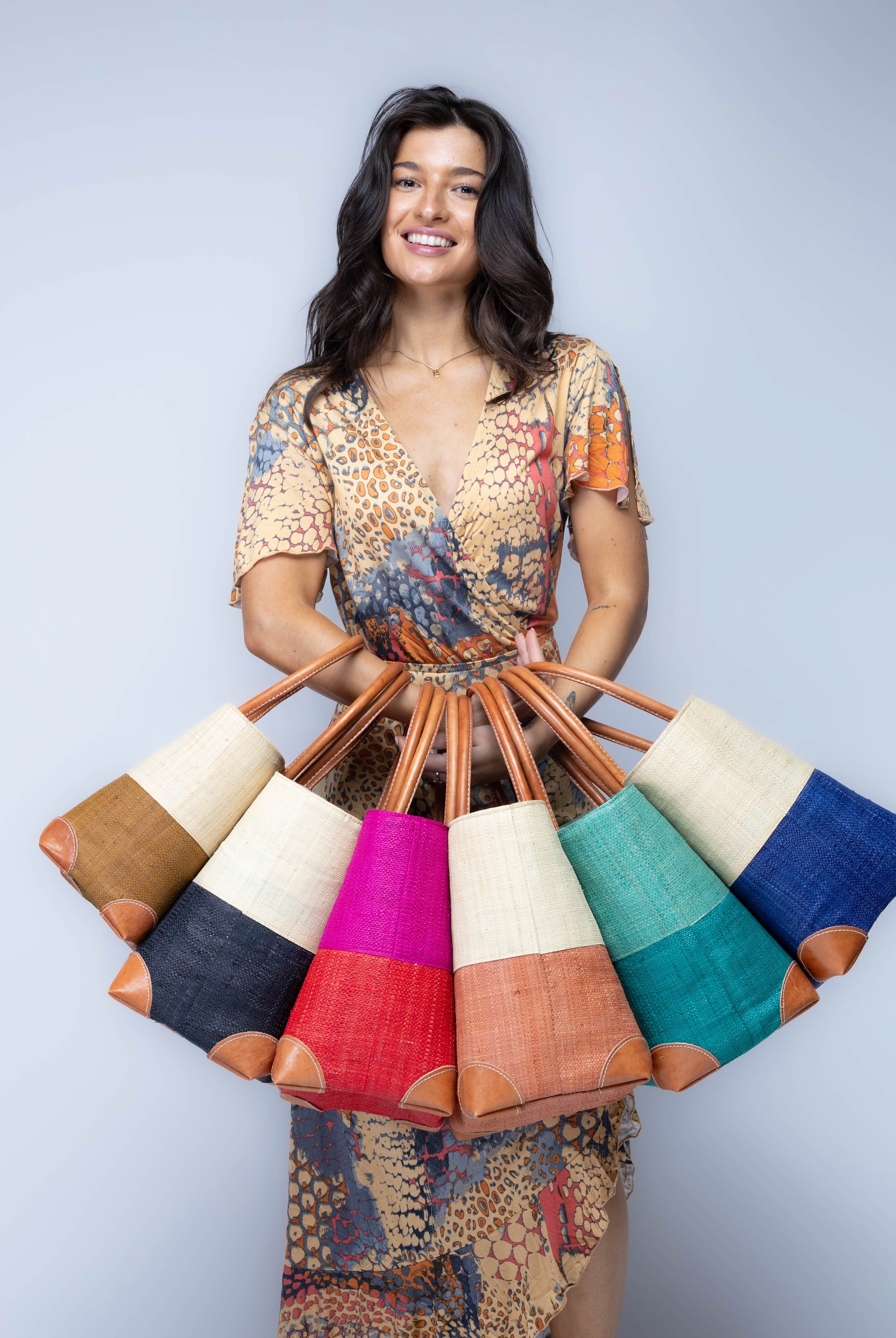 Model wearing multiple color options of Trinidad Two Tone Straw Basket Bags handmade loomed raffia palm fiber in a two tone color block patterns with leather handles and accents beach bag tote purse - Shebobo