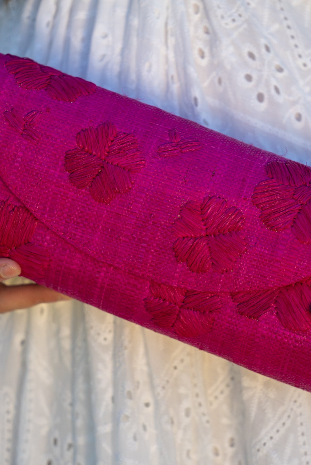 Model wearing Tulum Clutch Fuchsia hot/bright/barbie/pink Flower Embroidery handmade loomed raffia palm fibers with envelope clutch shape, embroidered multi-sized embroidered flower pattern, and assorted interior wax cloth African Print liners plus zippered pocket - Shebobo