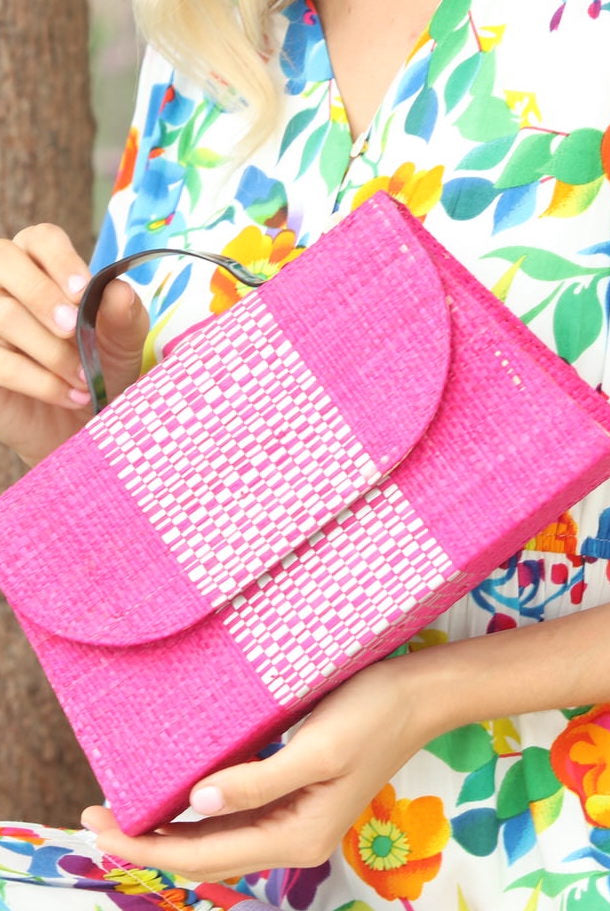 Model wearing Wynwood Fuchsia Straw Handbag with Metallic Detailing & Horn Handle handmade loomed raffia in fuchsia pink/hot pink/barbie pink and silver metallic vegan leather in three vertical bands of color with the metallic weave centered on the purse under the handles - Shebobo