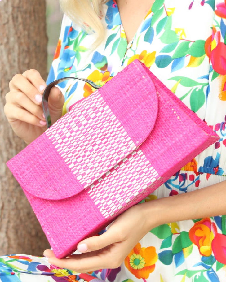 Model wearing Wynwood Fuchsia Straw Handbag with Metallic Detailing & Horn Handle handmade loomed raffia in fuchsia pink/hot pink/barbie pink and silver metallic vegan leather in three vertical bands of color with the metallic weave centered on the purse under the handles - Shebobo