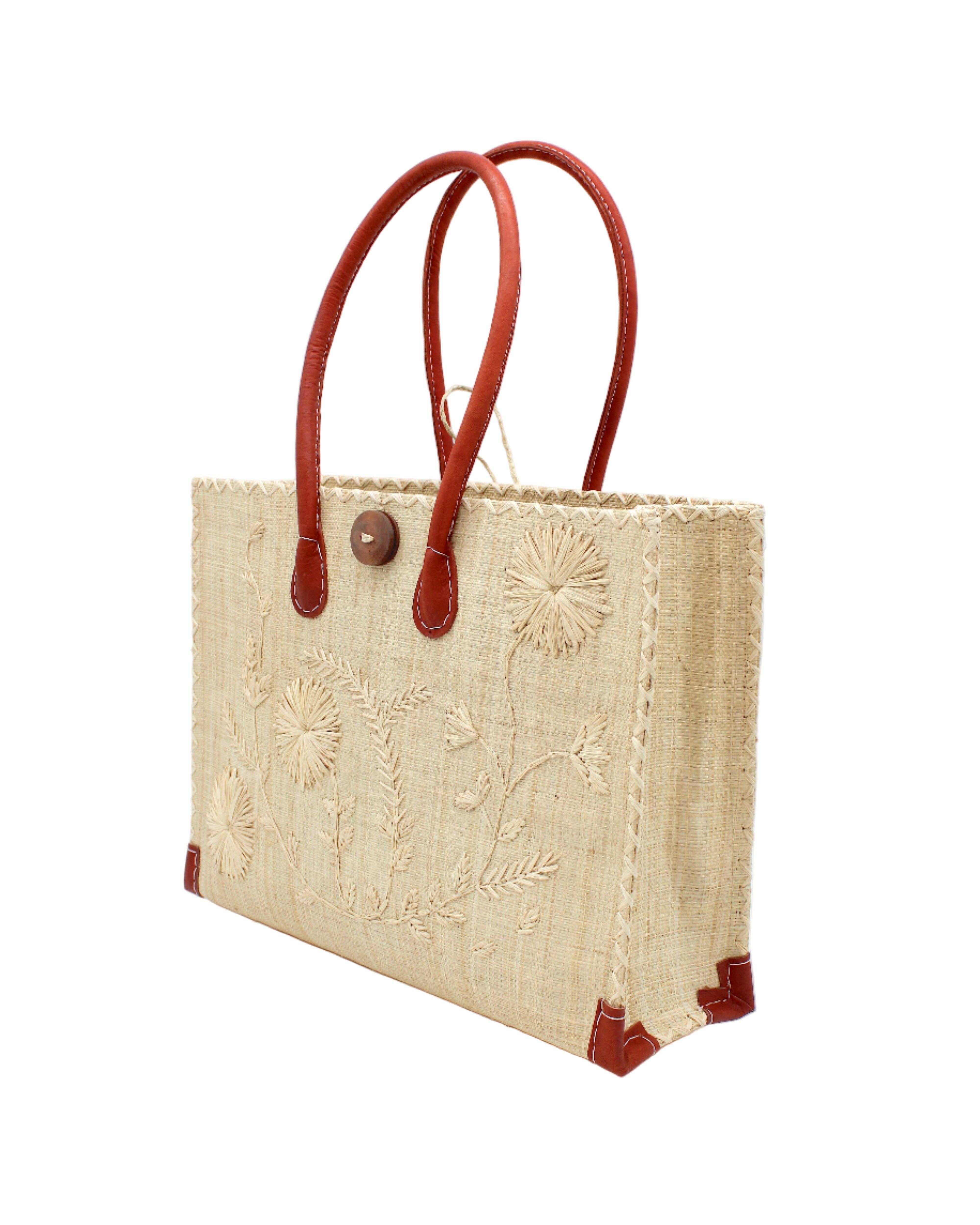 Side view Zafran Natural Embroidered Straw Beach Bag with Floral Pattern handmade natural raffia palm fiber in a solid hue of natural straw color with asymmetrical floral leaf, vine, and flower pattern in Natural with matching cross-stitch edging, leather handles, and wooden button closure shoulder bag handbag tote - Shebobo