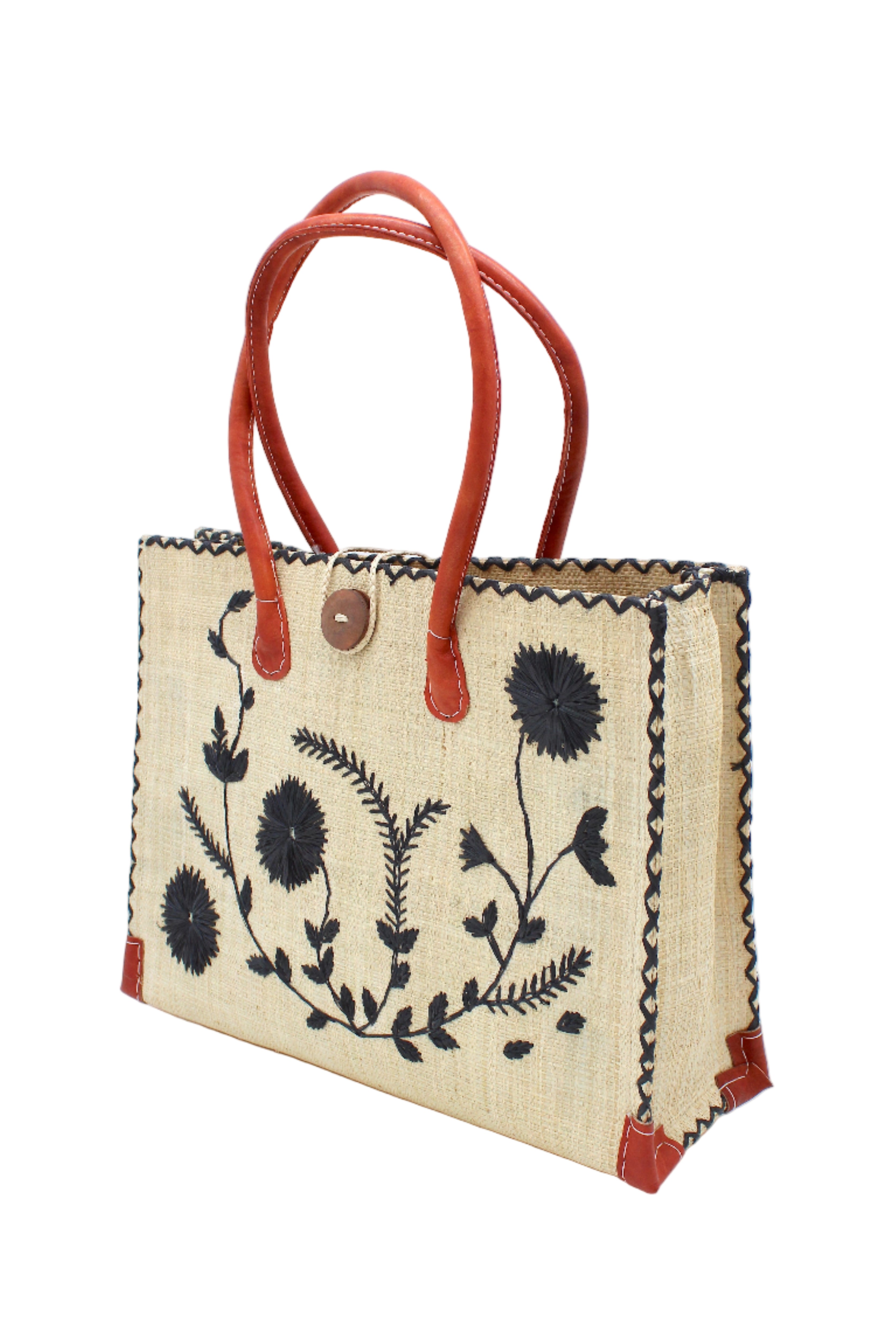 Side view Zafran Natural & Black Embroidered Straw Beach Bag with Floral Pattern handmade natural raffia palm fiber in a solid hue of natural straw color with asymmetrical floral leaf, vine, and flower pattern in black with matching cross-stitch edging, leather handles, and wooden button closure shoulder bag handbag tote - Shebobo