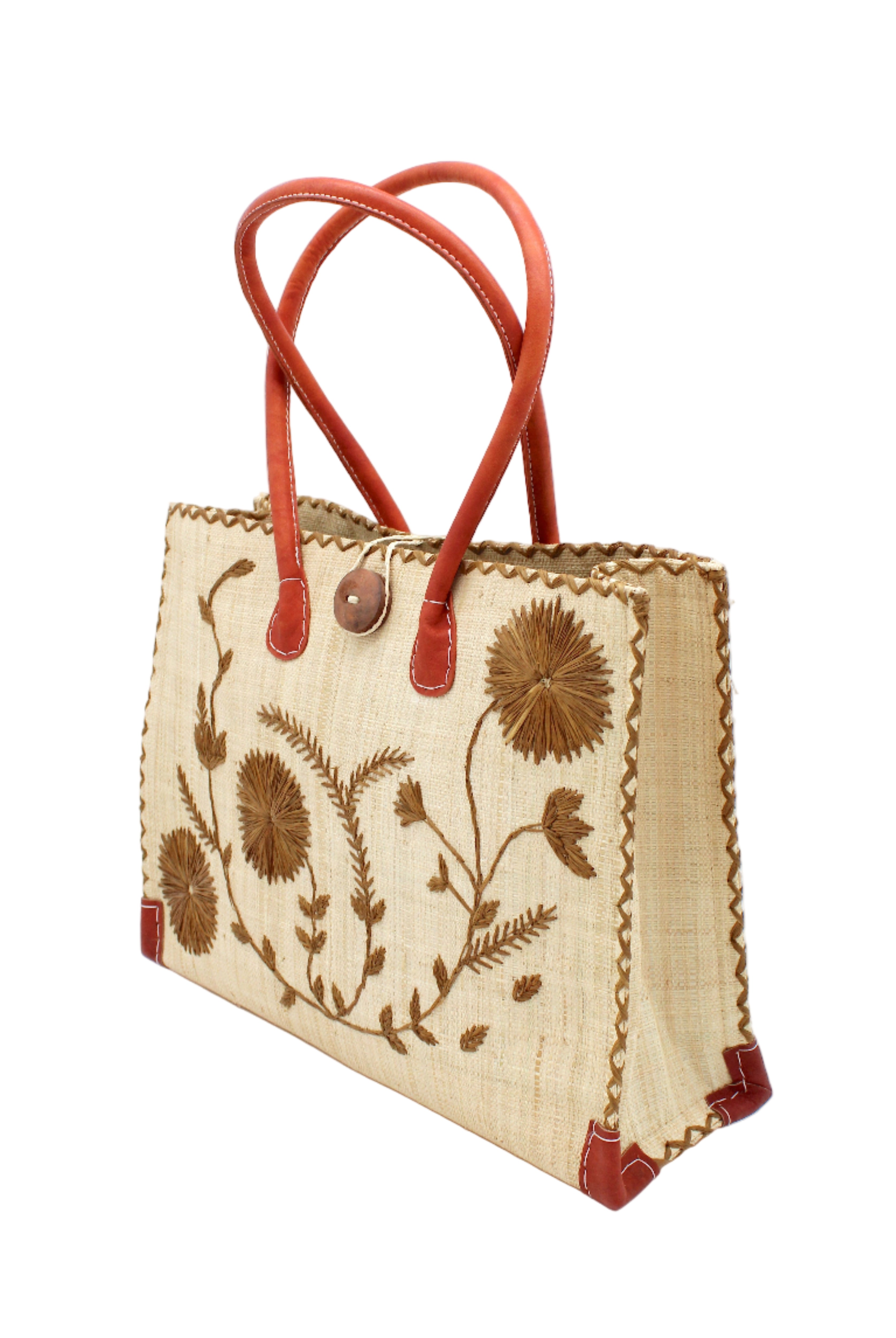 Side view Zafran Natural & Cinnamon Embroidered Straw Beach Bag with Floral Pattern handmade natural raffia palm fiber in a solid hue of natural straw color with asymmetrical floral leaf, vine, and flower pattern in cinnamon tobacco/dark/brown with matching cross-stitch edging, leather handles, and wooden button closure shoulder bag handbag tote - Shebobo
