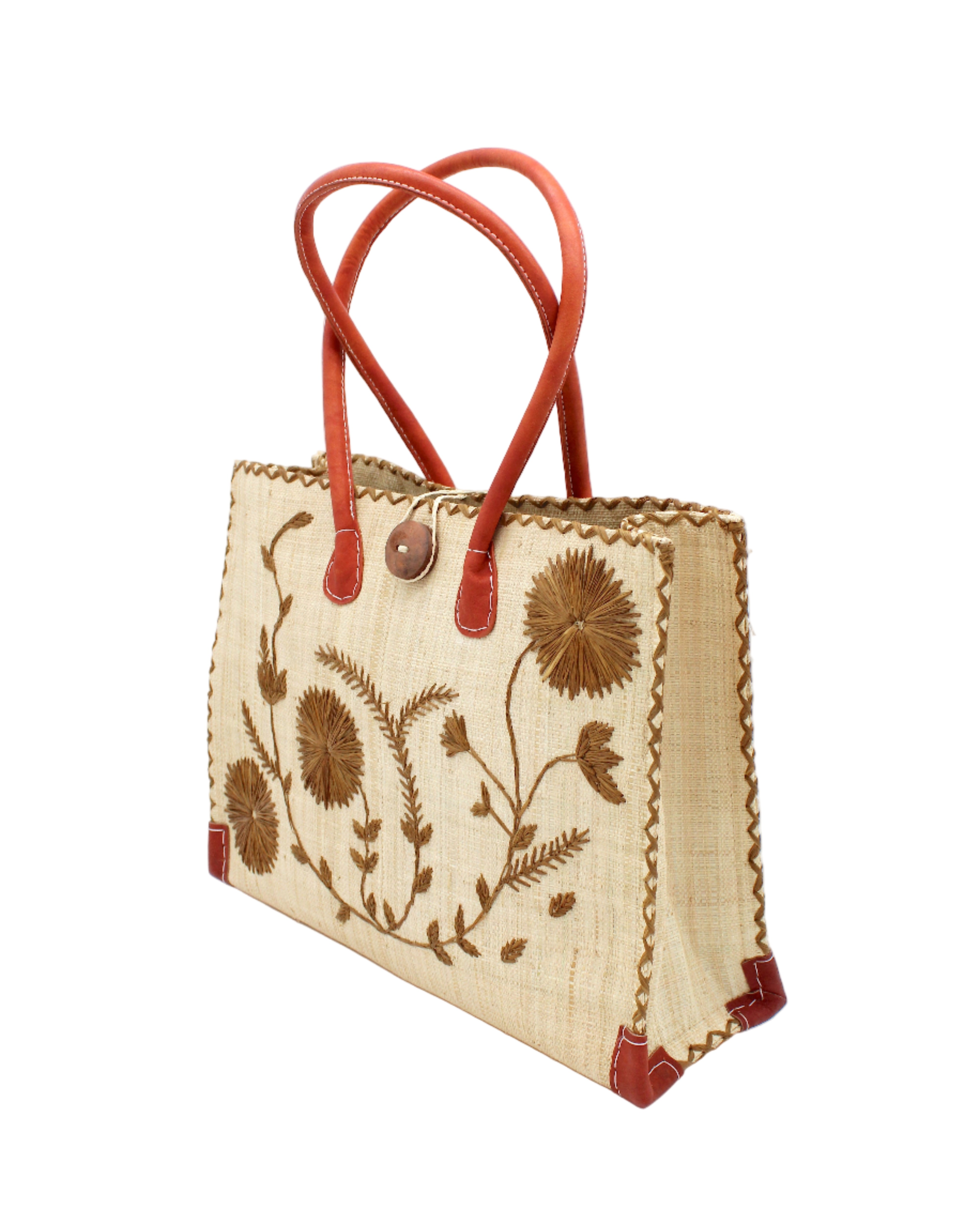Side view Zafran Natural & Cinnamon Embroidered Straw Beach Bag with Floral Pattern handmade natural raffia palm fiber in a solid hue of natural straw color with asymmetrical floral leaf, vine, and flower pattern in cinnamon tobacco/dark/brown with matching cross-stitch edging, leather handles, and wooden button closure shoulder bag handbag tote - Shebobo