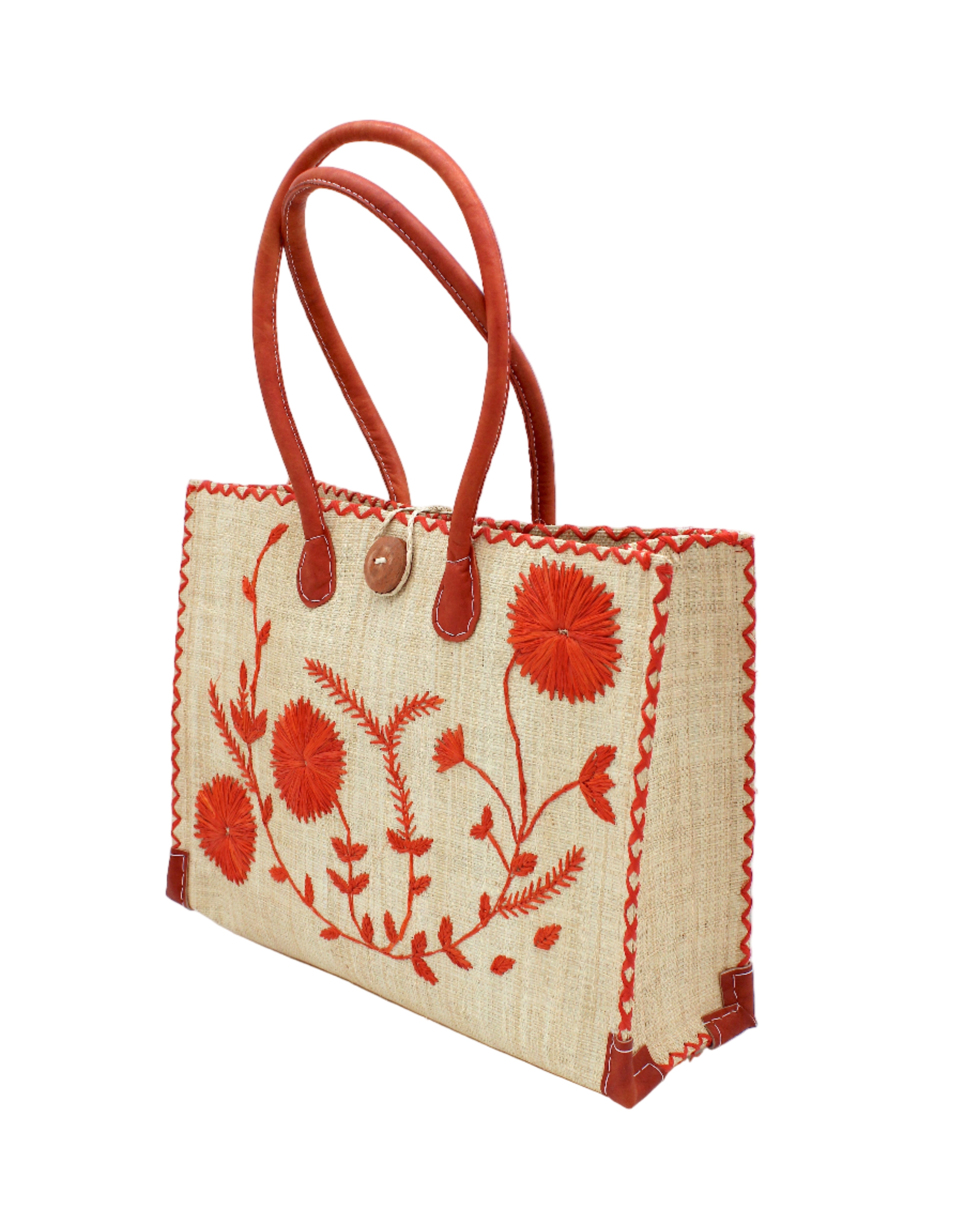 Side view Zafran Natural & Coral Embroidered Straw Beach Bag with Floral Pattern handmade natural raffia palm fiber in a solid hue of natural straw color with asymmetrical floral leaf, vine, and flower pattern in coral orange/red with matching cross-stitch edging, leather handles, and wooden button closure shoulder bag handbag tote - Shebobo