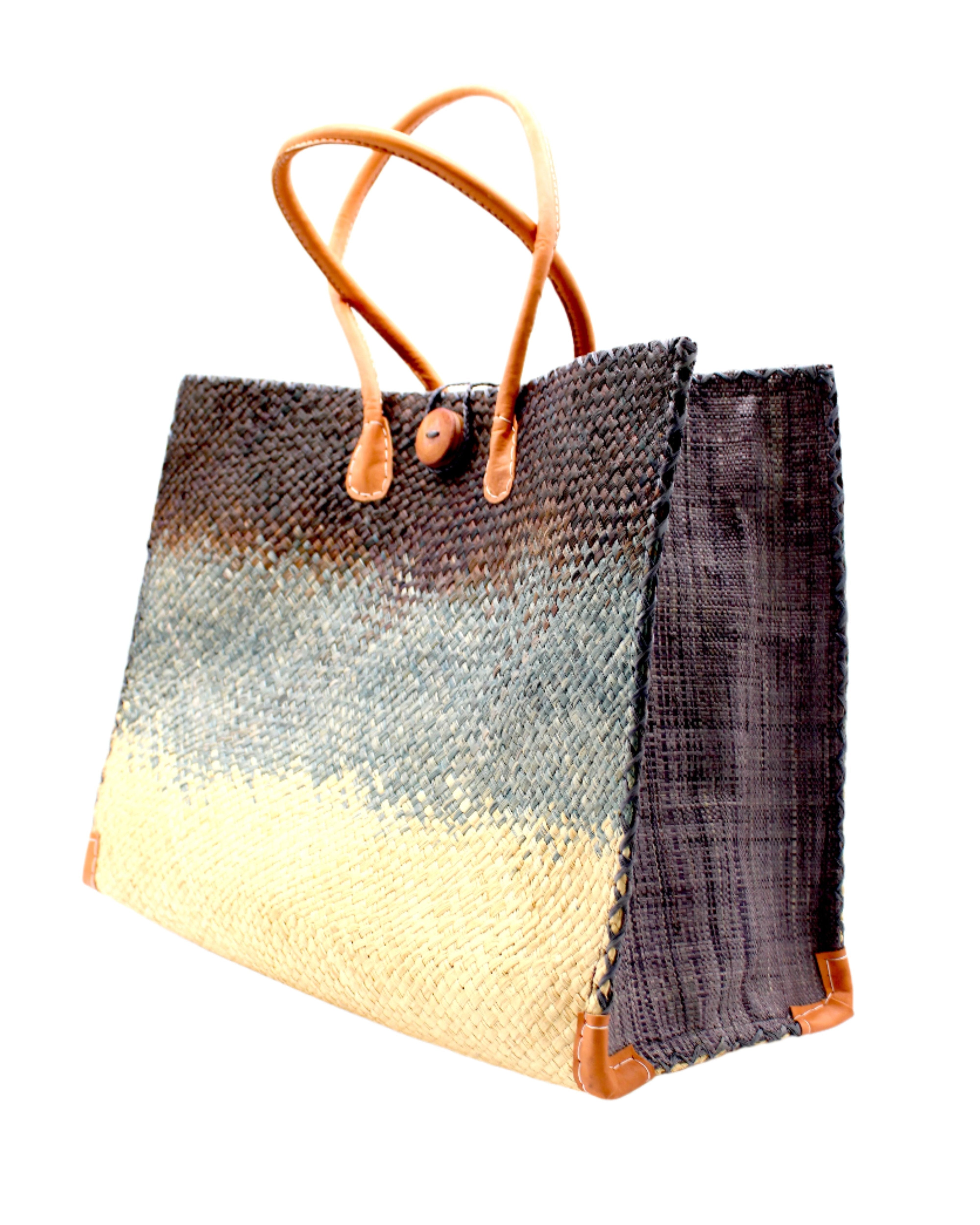 Side View Holden Black Ombre Zafran Straw Beach Bags handmade dip dyed raffia woven into a three part horizontal ombre pattern of black on the top, grey in the middle and both sides, and natural on the bottom with cross stitch edging, wooden button, and leather handles - Shebobo