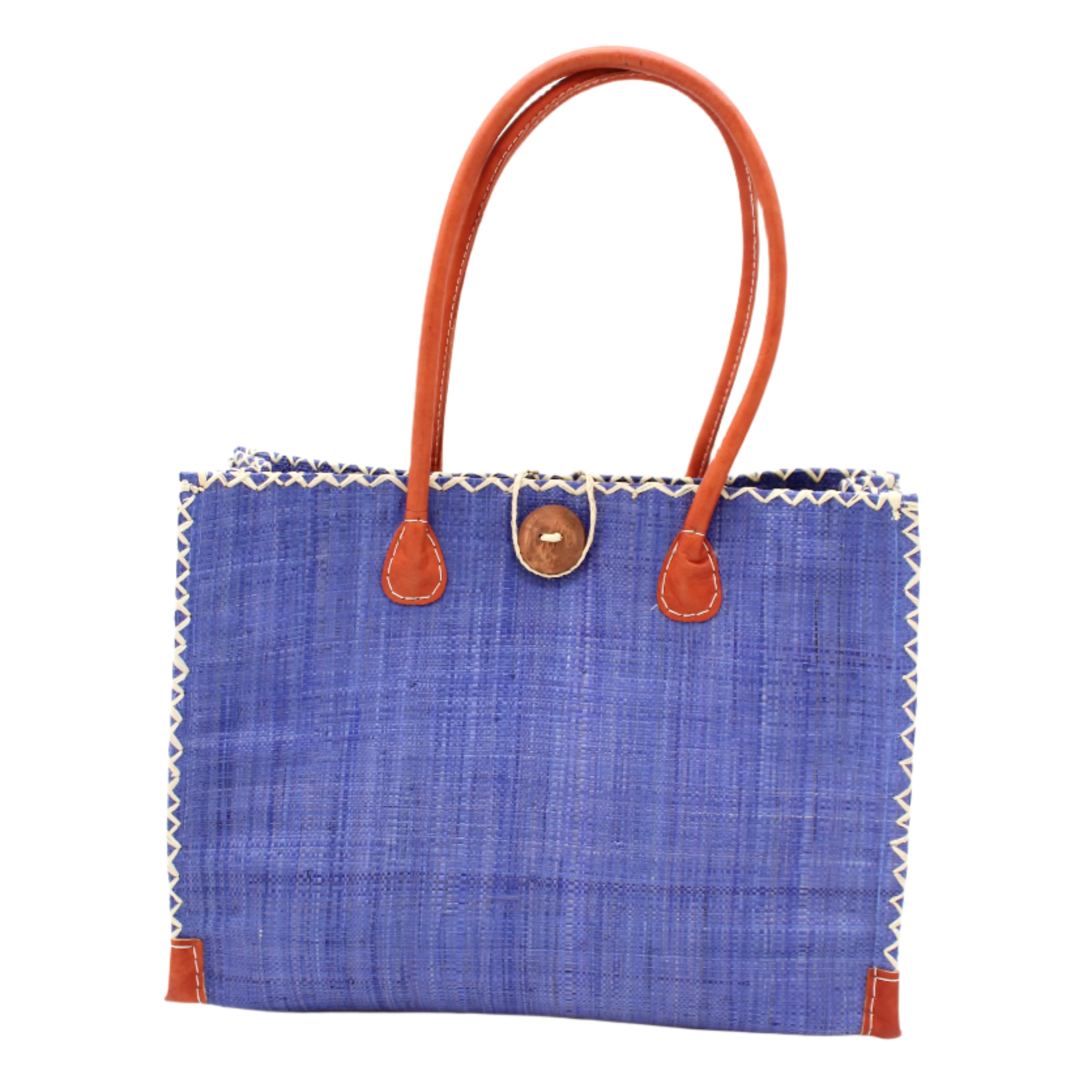 Zafran Straw Beach Bag with Plastic Liner handmade loomed raffia in a solid hue of Denim retro/light/blue with contrasting natural straw color cross stitch edge binding, wood button closure, and leather handles & feet plus assorted print plastic lining - Shebobo