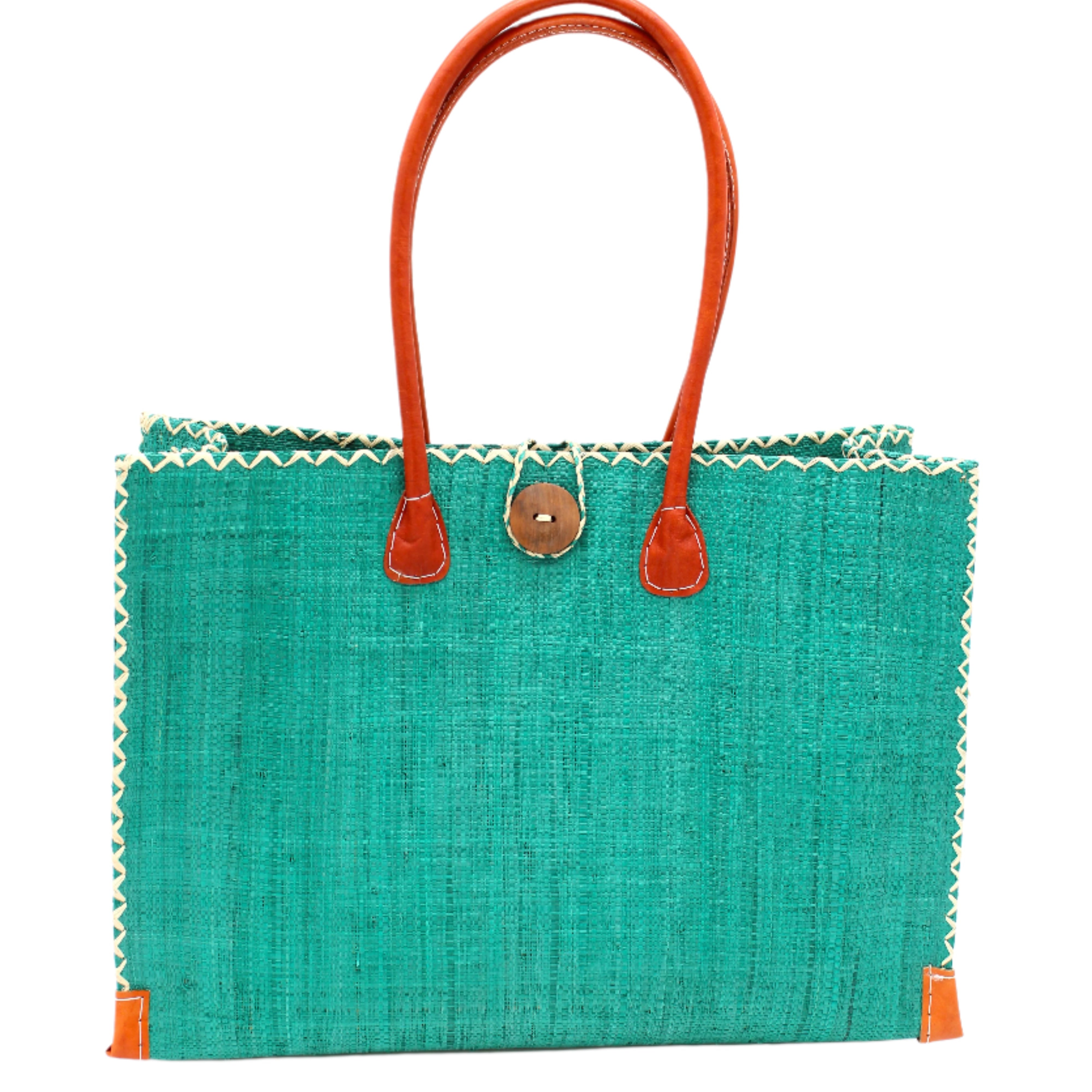 Zafran Straw Beach Bag with Plastic Liner handmade loomed raffia in a solid hue of Teal dark/blue/green with contrasting natural straw color cross stitch edge binding, wood button closure, and leather handles & feet plus assorted print plastic lining - Shebobo