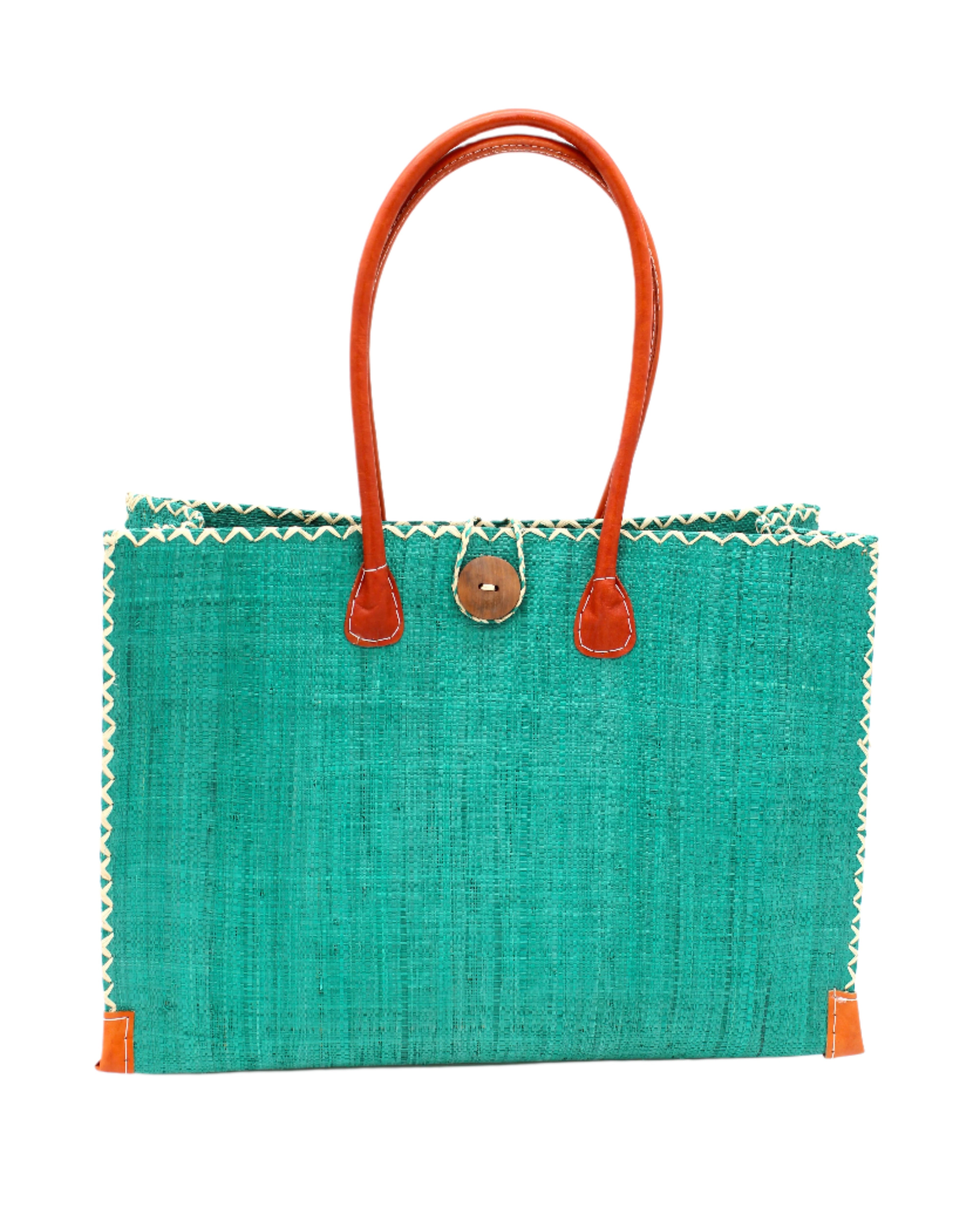 Zafran Straw Beach Bag with Plastic Liner handmade loomed raffia in a solid hue of Teal dark/blue/green with contrasting natural straw color cross stitch edge binding, wood button closure, and leather handles & feet plus assorted print plastic lining - Shebobo