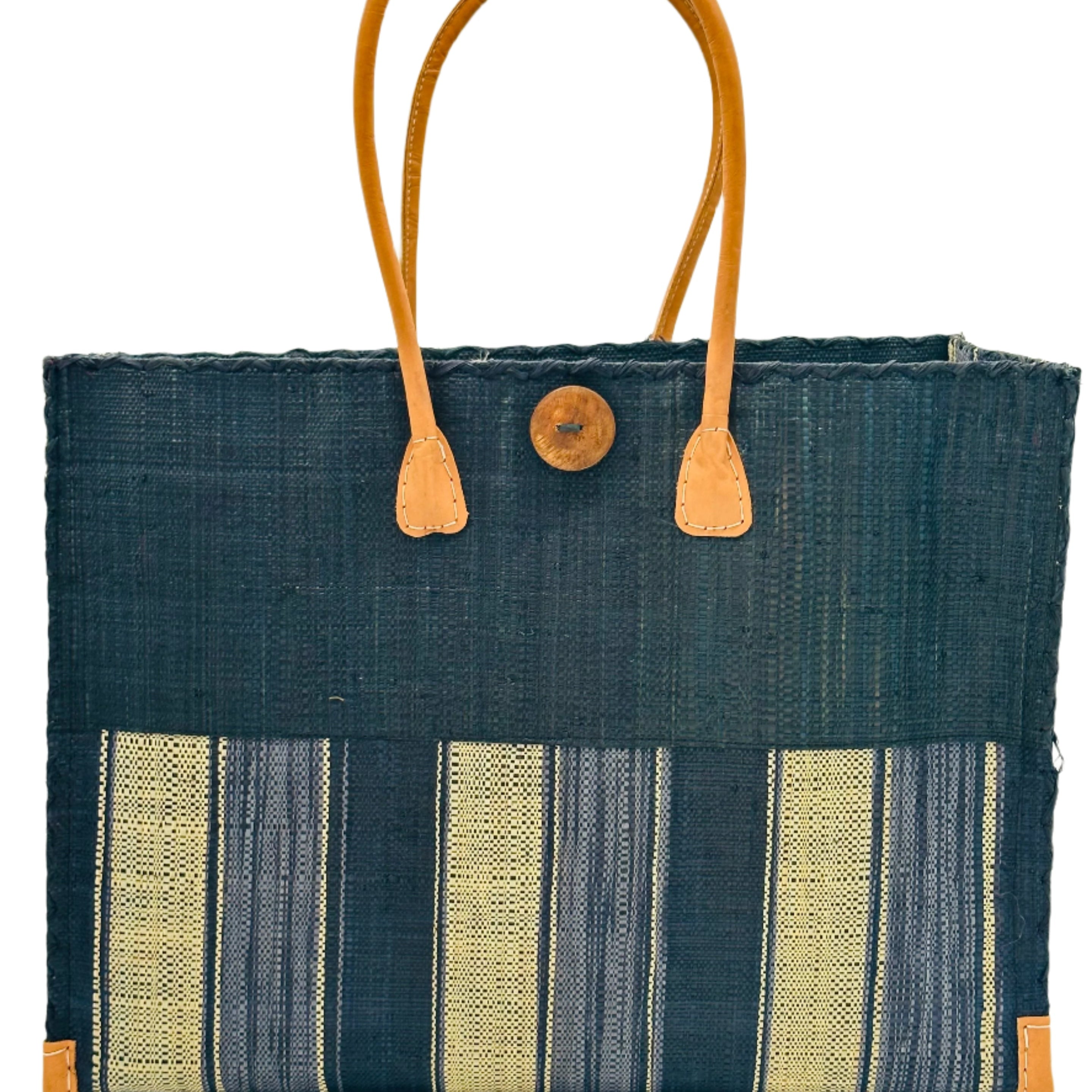 Zafran Two Tone Wide Stripe Black Swirl Straw Beach Bag handmade loomed raffia palm fiber in a solid hue of black on the top half of the bag and a multicolor multi-width vertical stripe pattern of black, grey, and natural straw color on the bottom half of the bag with leather handles and feet and matching crosshatch stitch edging shoulder bag - Shebobo