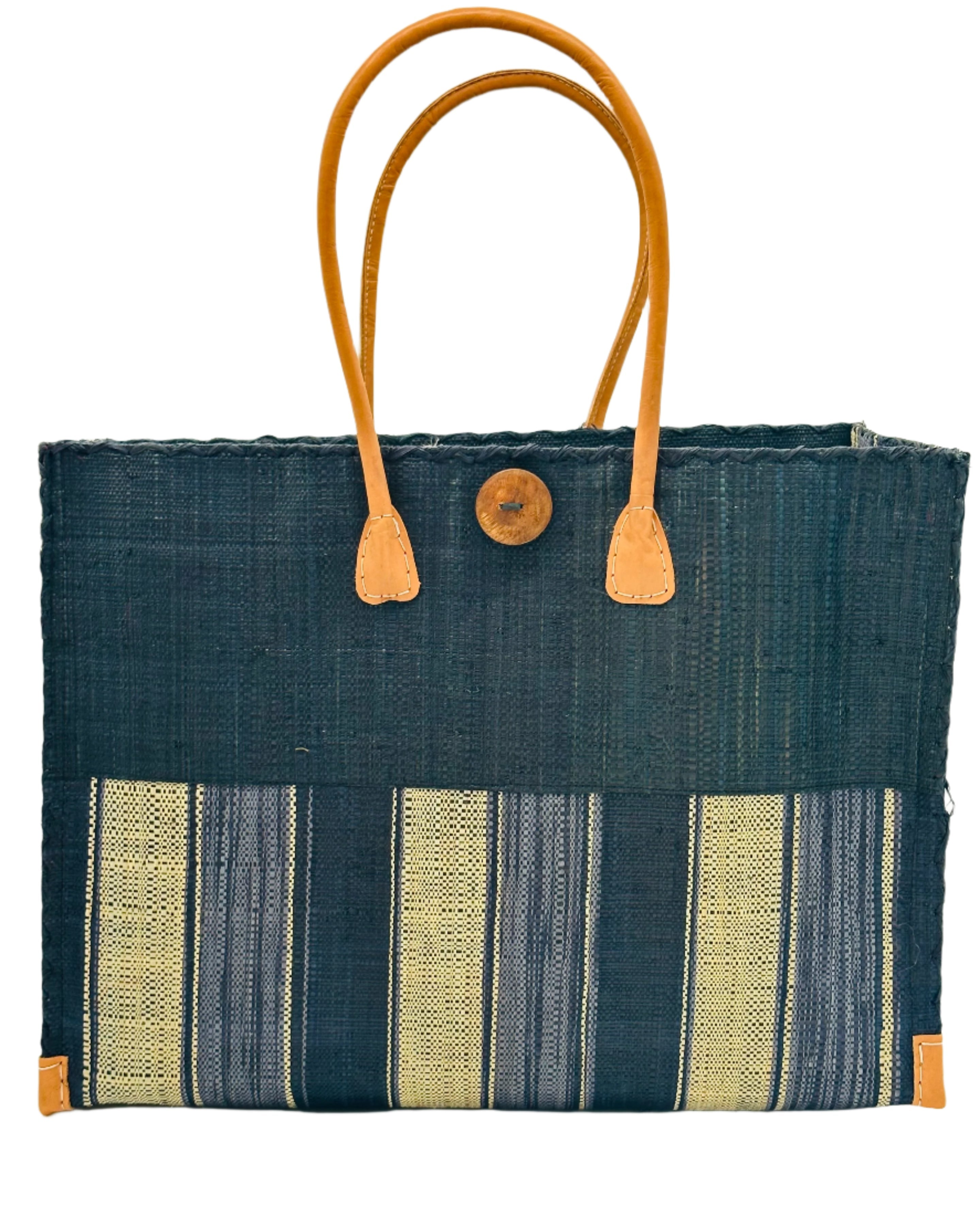 Zafran Two Tone Wide Stripe Black Swirl Straw Beach Bag handmade loomed raffia palm fiber in a solid hue of black on the top half of the bag and a multicolor multi-width vertical stripe pattern of black, grey, and natural straw color on the bottom half of the bag with leather handles and feet and matching crosshatch stitch edging shoulder bag - Shebobo