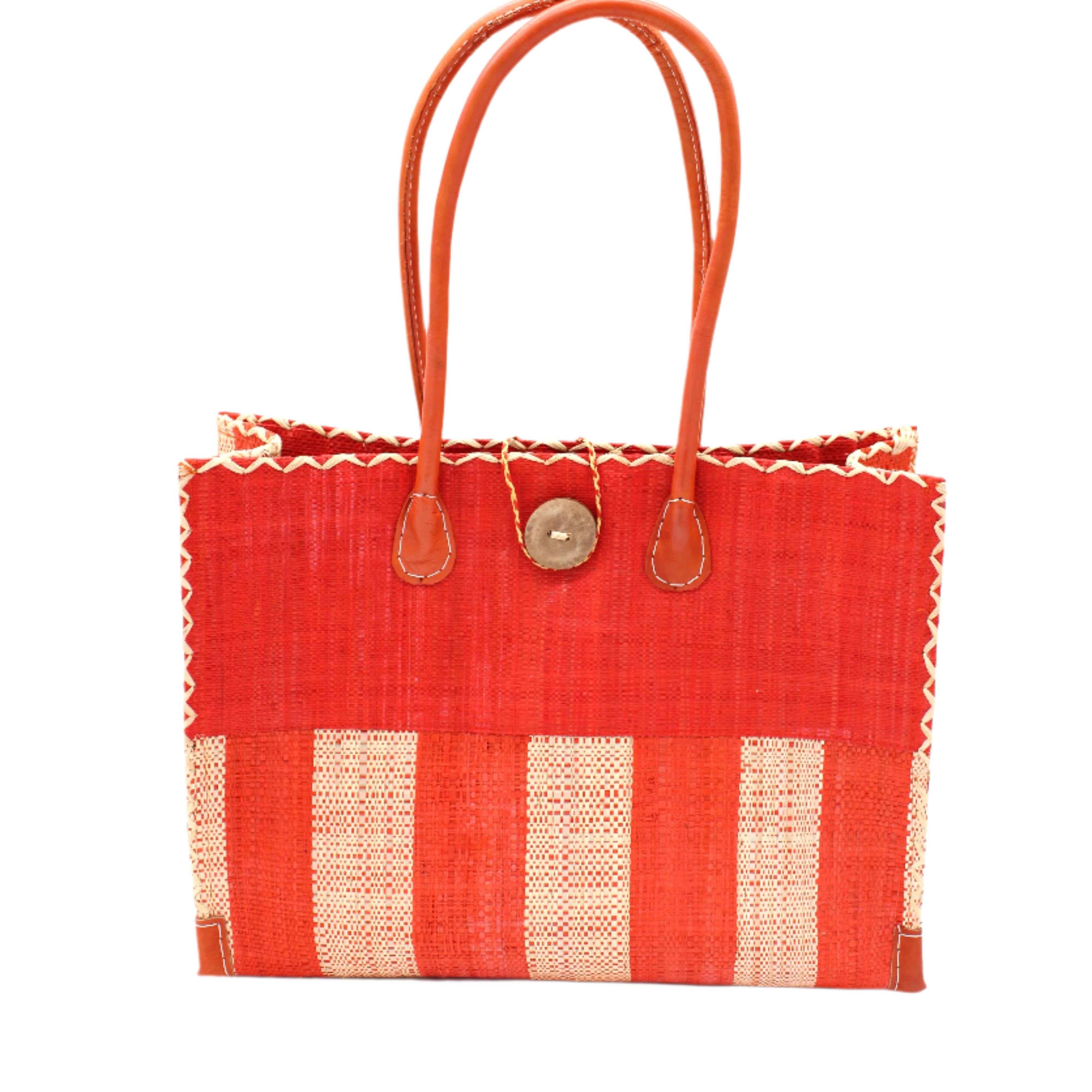 Zafran Two Tone Wide Stripe Coral and Natural Straw Beach Bag handmade loomed raffia palm fiber in a solid hue of coral orange/red on the top half of the bag and a two tone even width vertical wide stripe pattern of coral and natural straw color on the bottom half of the bag with leather handles and feet and matching crosshatch stitch edging shoulder bag - Shebobo