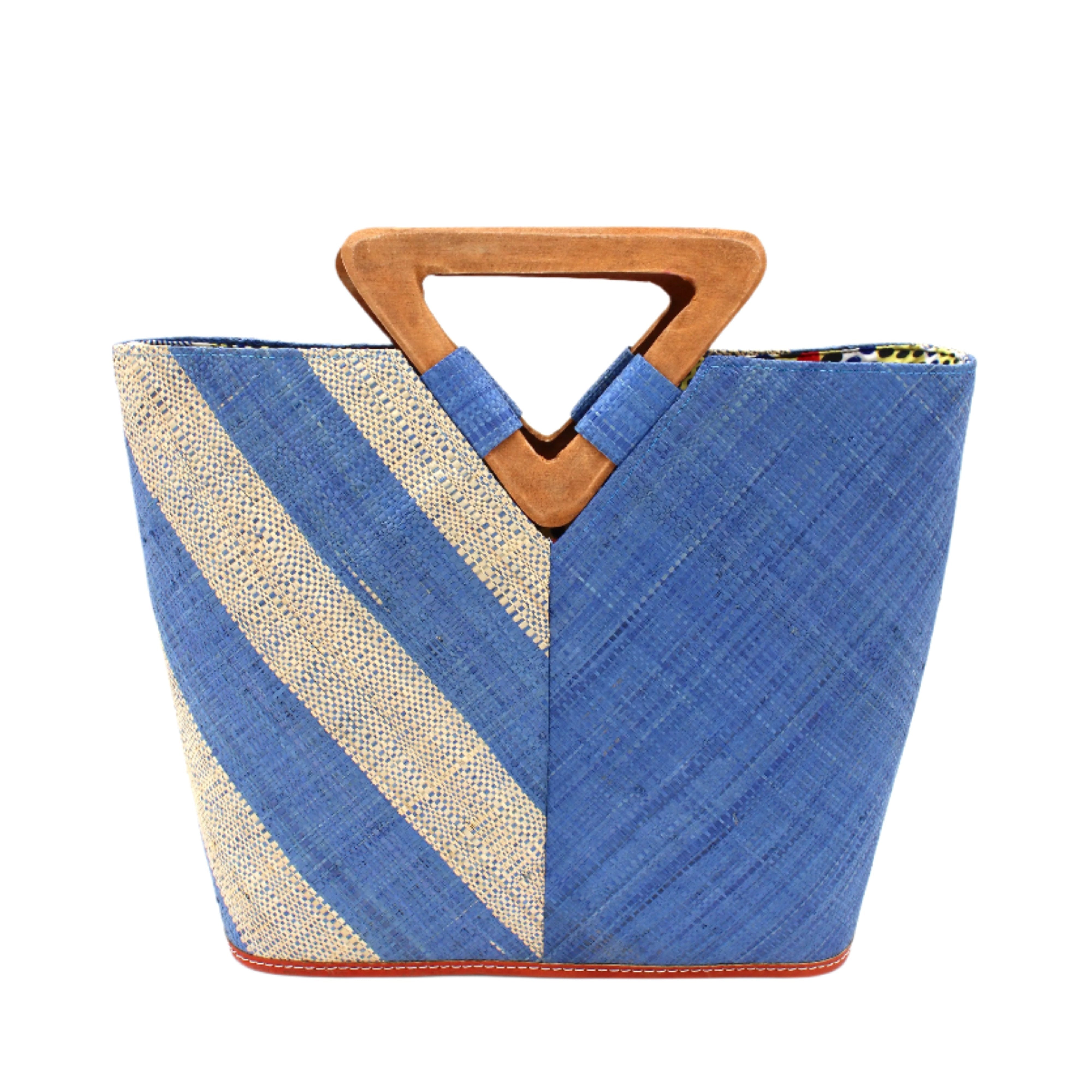 Zuki Two Tone Denim Straw Handbag With Wood Triangle Handle handmade loomed raffia palm fiber in a two tone pattern with the left half of the bag even width stripes of denim retro/light/blue and natural straw color oriented as a diagonal stripe and the right half of the bag a solid hue of denim with carved wood handles - Shebobo