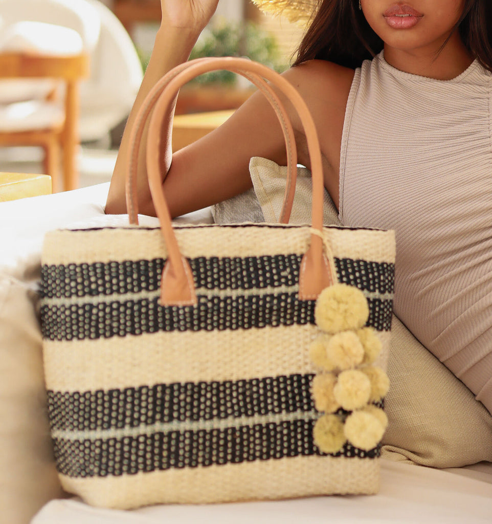 Model wearing Imperial Sisal basket bag with waterfall pompom charm - natural, black, and grey multi sized woven stripe pattern  - Shebobo