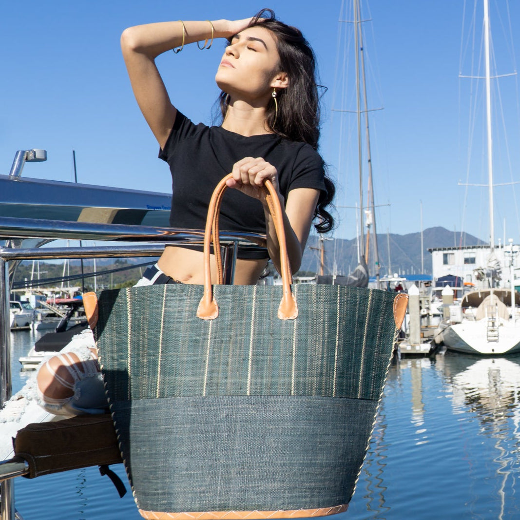 model wearing Santa Cruz Two Tone Large Straw Tote Bag handmade beach bag loomed raffia solid grey bottom with grey and natural vertical pinstripe pattern top plus leather handles xl handbag - Shebobo