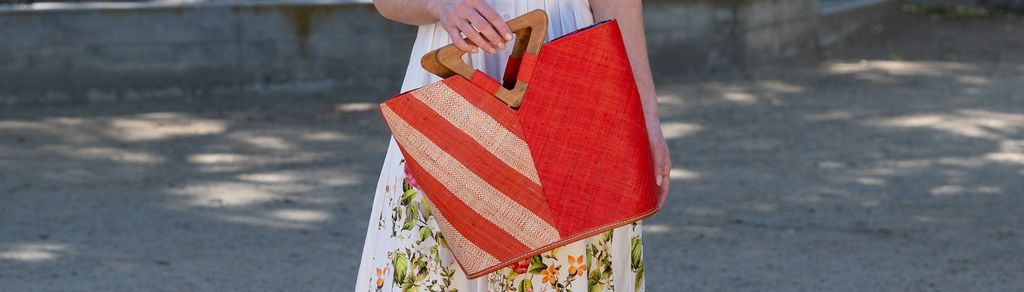 Model wearing Monte Carlo Wynwood Big Straw Beach Bag with Metallic Detailing Red Shoulder Bag handmade loomed raffia palm fiber in a solid hue of Red with incorporated woven in vegan leather gold metallic strands and leather handles purse - Shebobo