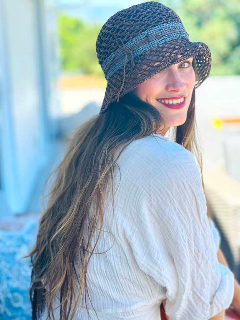 Model wearing 2.5" Brim Maria Cinnamon Crochet Bucket Straw Hat handmade raffia palm fiber crochet in an open loop wave/shell pattern of cinnamon/tobacco/brown with a close weave crochet hat band in contrasting dark grey with adjustable hat band straw sun hat - Shebobo