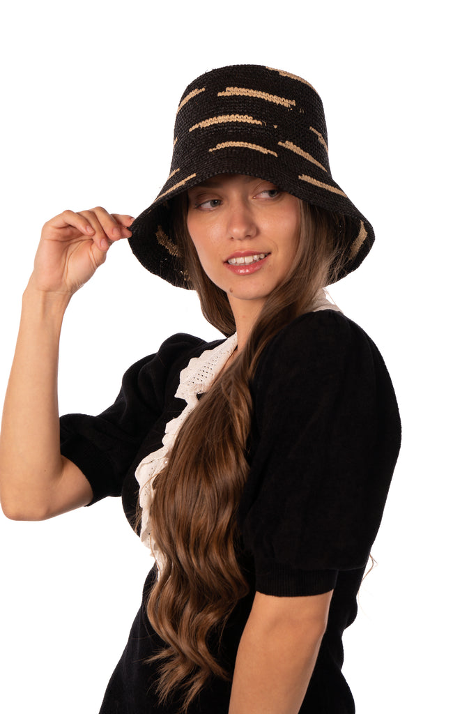 Model wearing 2.5" Brim Taylor Black Crochet Bucket Straw Hat with Zebra Stripes handmade raffia palm fiber in a two tone color combination of horizontal short stripes that create a dash pattern around the hat in black with natural straw color - Shebobo