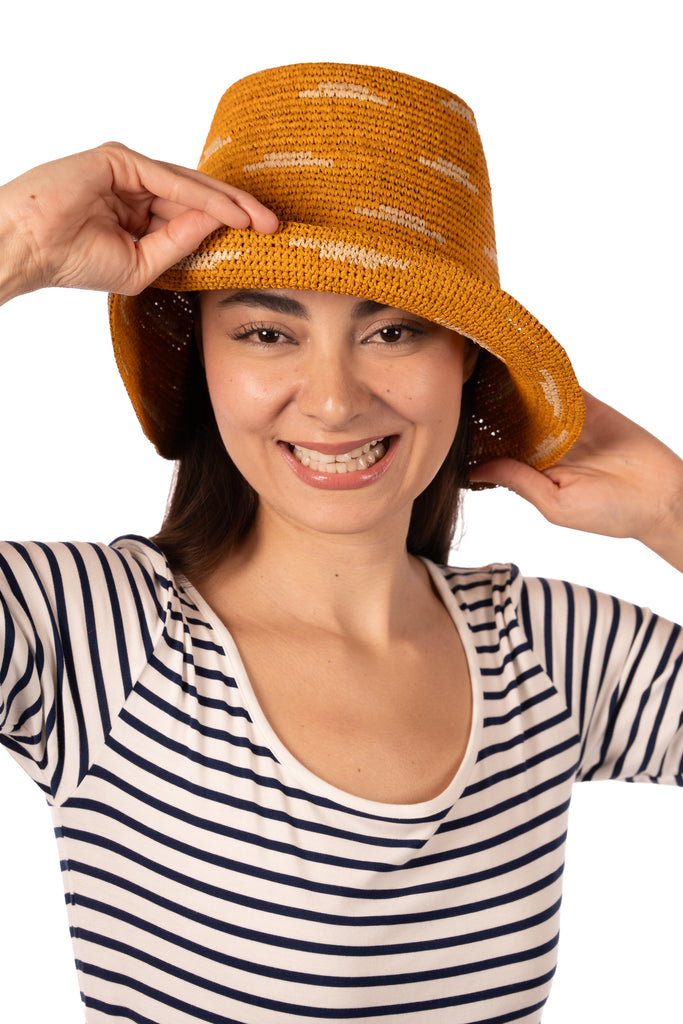 Model wearing 2.5" Brim Taylor Saffron Crochet Bucket Straw Hat with Zebra Stripes handmade raffia palm fiber in a two tone color combination of horizontal short stripes that create a dash pattern around the hat in saffron yellow/orange with natural straw color - Shebobo