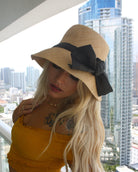 Model Wearing Cara Big Bow Straw Hat Handmade loomed raffia straw hat solid natural bucket hat with large black bow - Shebobo