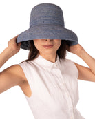 Model wearing Leor Denim crochet straw hat handmade woven natural raffia palm fiber in a solid hue of denim/retro/light/blue color 3" brim packable straw hat with matching adjustable braided hat band - Shebobo