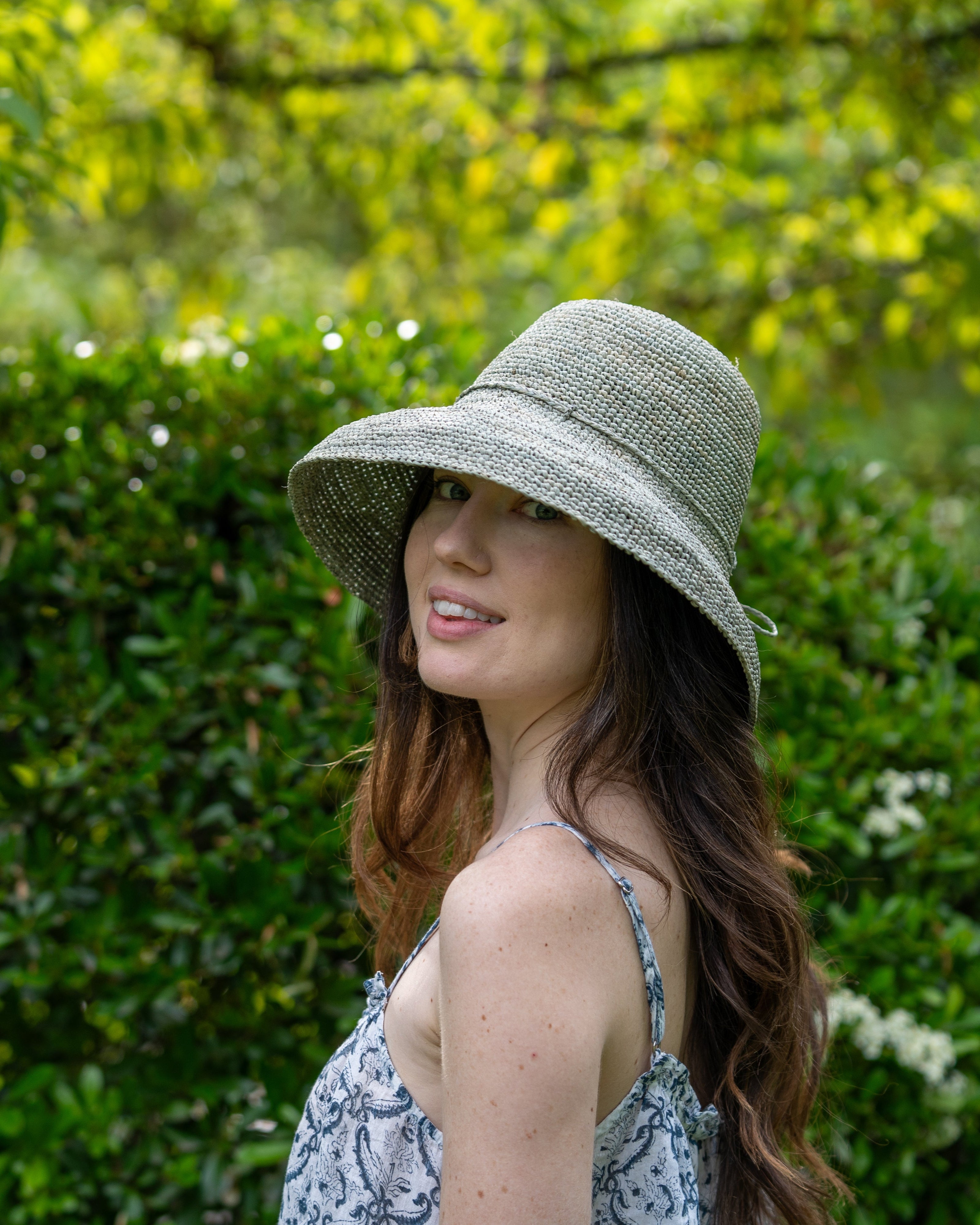 Model wearing Leor Ocean Mist crochet straw hat handmade woven natural raffia palm fiber in a solid hue of ocean mist/sage/pale/grey green color 3" brim packable straw hat with matching adjustable braided hat band - Shebobo