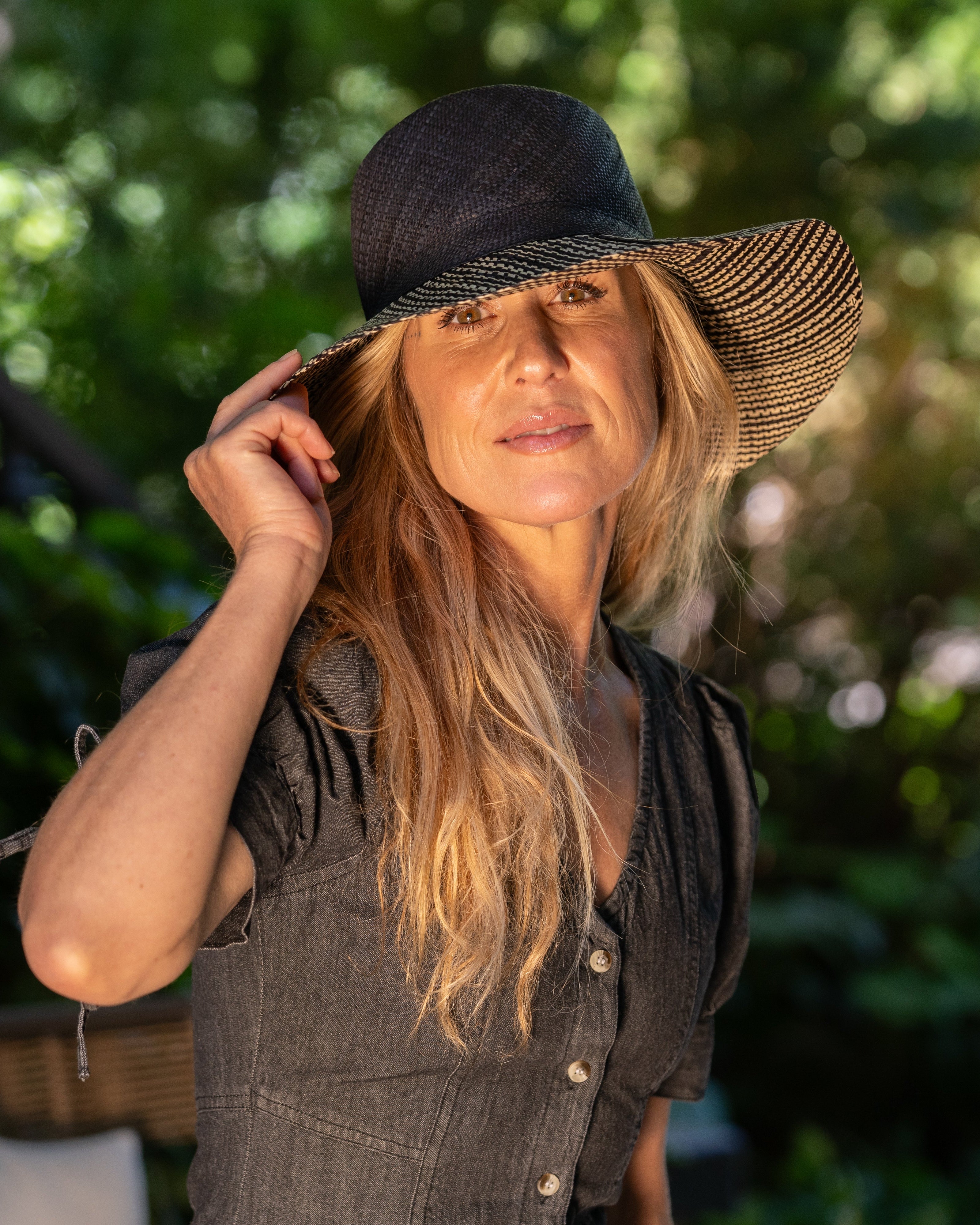 Model wearing 3" Brim Marsea Black Two Tone Melange Straw Sun Hats handmade loomed natural raffia palm fiber in a two tone color block aesthetic of solid black on the crown and hatband with multicolor melange heathered pattern swirl of black and natural straw color on the brim lightweight breathable packable hat - Shebobo