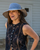 Model wearing 3" Brim Marsea Denim Two Tone Melange Straw Sun Hats handmade loomed natural raffia palm fiber in a two tone color block aesthetic of solid denim retro/light/ blue on the crown and hatband with multicolor melange heathered pattern swirl of denim and natural straw color on the brim lightweight breathable packable hat - Shebobo