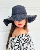 Model wearing 4" Brim Genevieve Black Crochet Straw Sun Hat with Lace Weave Edge handmade raffia palm fiber crochet solid hue black rounded crown with detailed lace weave edge and matching adjustable hat band - Shebobo