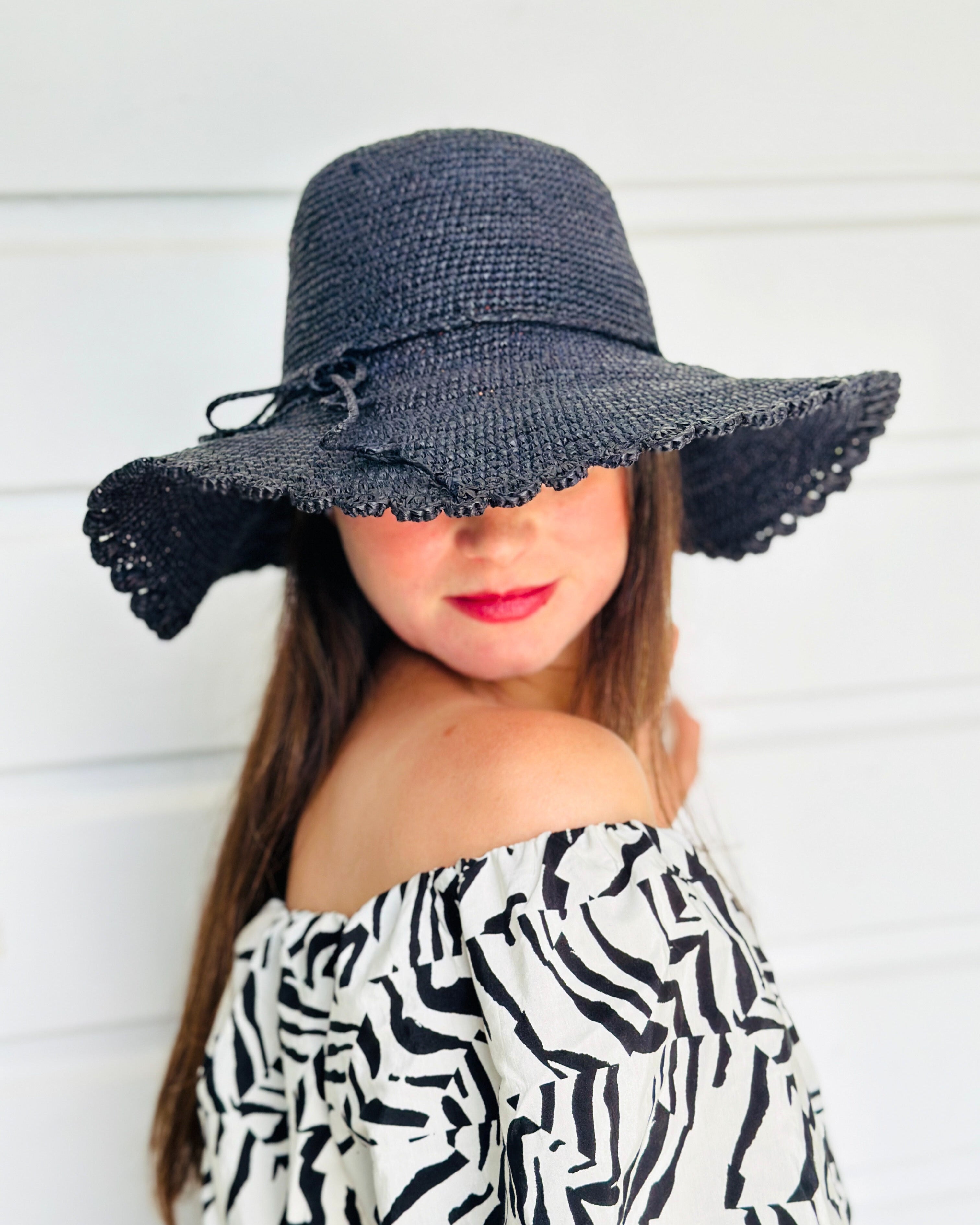 Model wearing 4" Brim Genevieve Black Crochet Straw Sun Hat with Lace Weave Edge handmade raffia palm fiber crochet solid hue black rounded crown with detailed lace weave edge and matching adjustable hat band - Shebobo