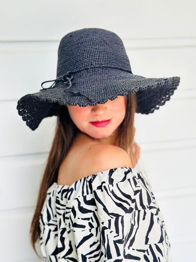 Model wearing 4" Brim Genevieve Black Crochet Straw Sun Hat with Lace Weave Edge handmade raffia palm fiber crochet solid hue black rounded crown with detailed lace weave edge and matching adjustable hat band - Shebobo