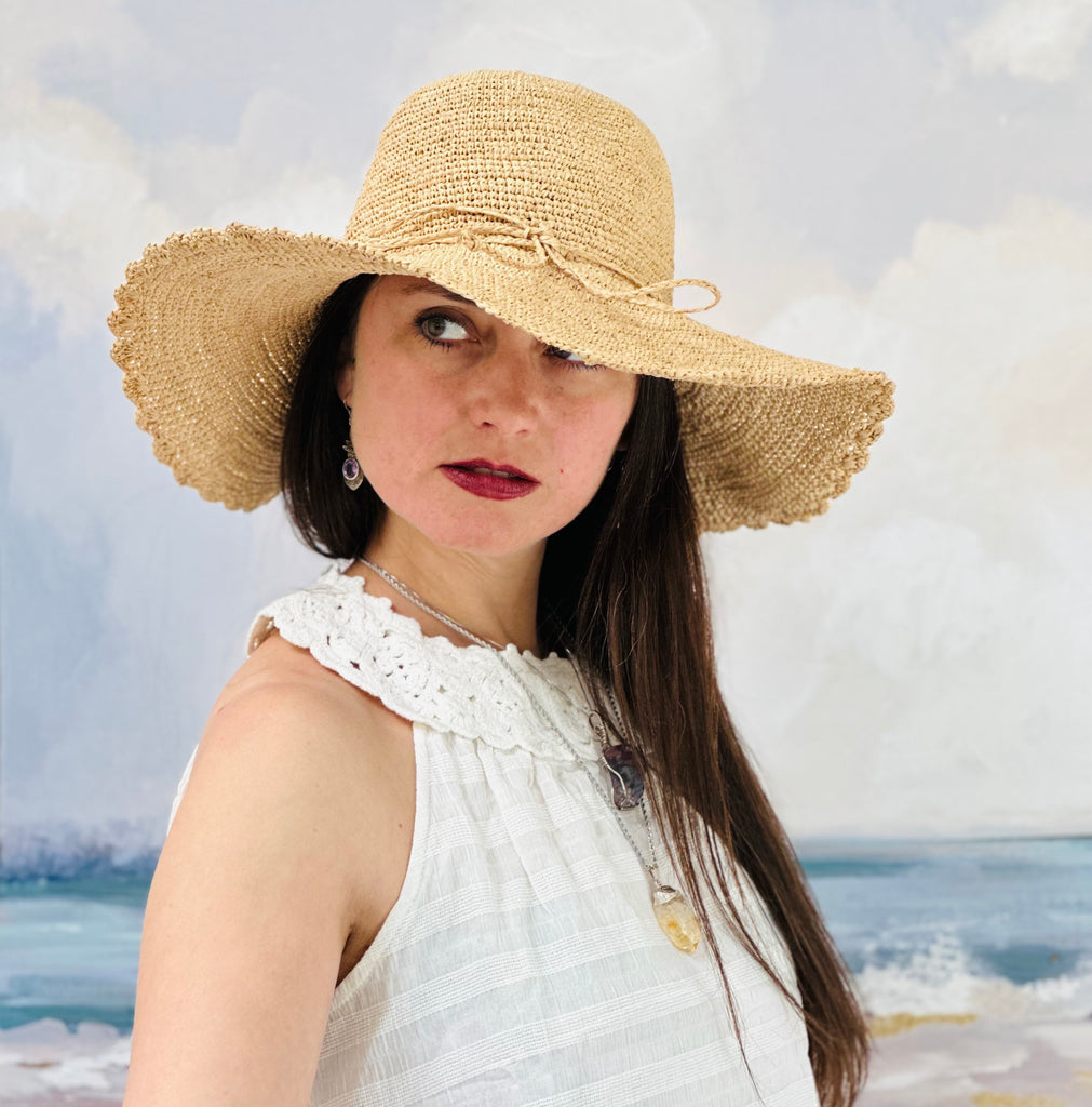 Model wearing 4" Brim Genevieve Natural Crochet Straw Sun Hat with Lace Weave Edge handmade raffia palm fiber crochet solid hue natural straw color rounded crown with detailed lace weave edge and matching adjustable hat band - Shebobo