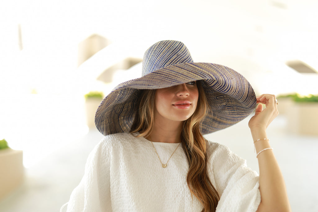 Model wearing 7 inch Wide Brim Blue Two Tone Melange Packable Straw Sun Hat handmade loomed raffia in a multicolor heathered melange pattern of navy blue and natural straw color creates a subtle swirl - Shebobo