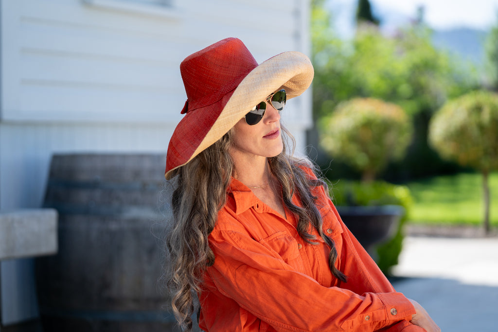 Model wearing 7" Brim Two Tone Coral red/orange Straw Hat handmade loomed raffia color block pattern of the top half coral orange/red and the bottom half natural straw color - Shebobo
